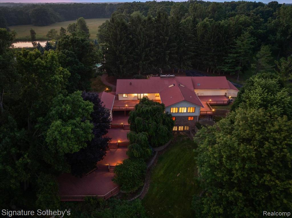 7255 E Baldwin Rd—a remarkable 107.7-acre country estate designed for refined living, business, and recreation.  Just minutes from Grand Blanc, Goodrich, and I-75, this property features over 7K sqft of living space, a 4K sqft office building, 3 ponds, a tennis court, a pole barn, a pool, tillable land, & 15 wooded acres making it ideal for farming, equestrian pursuits, or a private retreat. As you drive the lamppost-lined driveway, you’ll pass a charming covered bridge over serene ponds, pole barn, & tennis court before arriving at your expansive ranch. Inside, beautiful hardwood floors lead you to the living & dining areas, where windows & door walls open onto descending levels of decking overlooking the property. The dining room features a stone fireplace & flows into the gourmet kitchen, complete with 2 refrigerators, a double oven, 2 dishwashers, dual islands, a walk-in pantry, & a butler’s pantry with a wine fridge & glassware storage. This kitchen is built for both everyday convenience & entertaining. The custom primary suite has deck access, a double-sided fireplace, a spa-like bath, a walk-in closet with stackable laundry, & an attached office, den, or nursery. The lower level includes a second primary suite with a walkout & four additional bedrooms with Jack&Jill baths, a sewing room, a library/rec room, & a laundry/storage room. The basement offers a bonus space perfect for a theater, game room, or gym. Outside, the multi-level decks overlook 2 picturesque ponds. The upper deck features a hot tub room, while a lower level provides outdoor furniture storage & potential for a cocktail or ice cream bar. The in-ground pool is set beside a train car, which could be transformed into a guest or pool house. The 4K sqft office building serves as a versatile workspace, guest house, or rental income property.  It features 2 large conference rooms, 2 private offices/bedrooms, a kitchen, a bathroom, & a cozy study with a fireplace. Experience the extraordinary lifestyle that 7255 E Baldwin Rd has to offer!