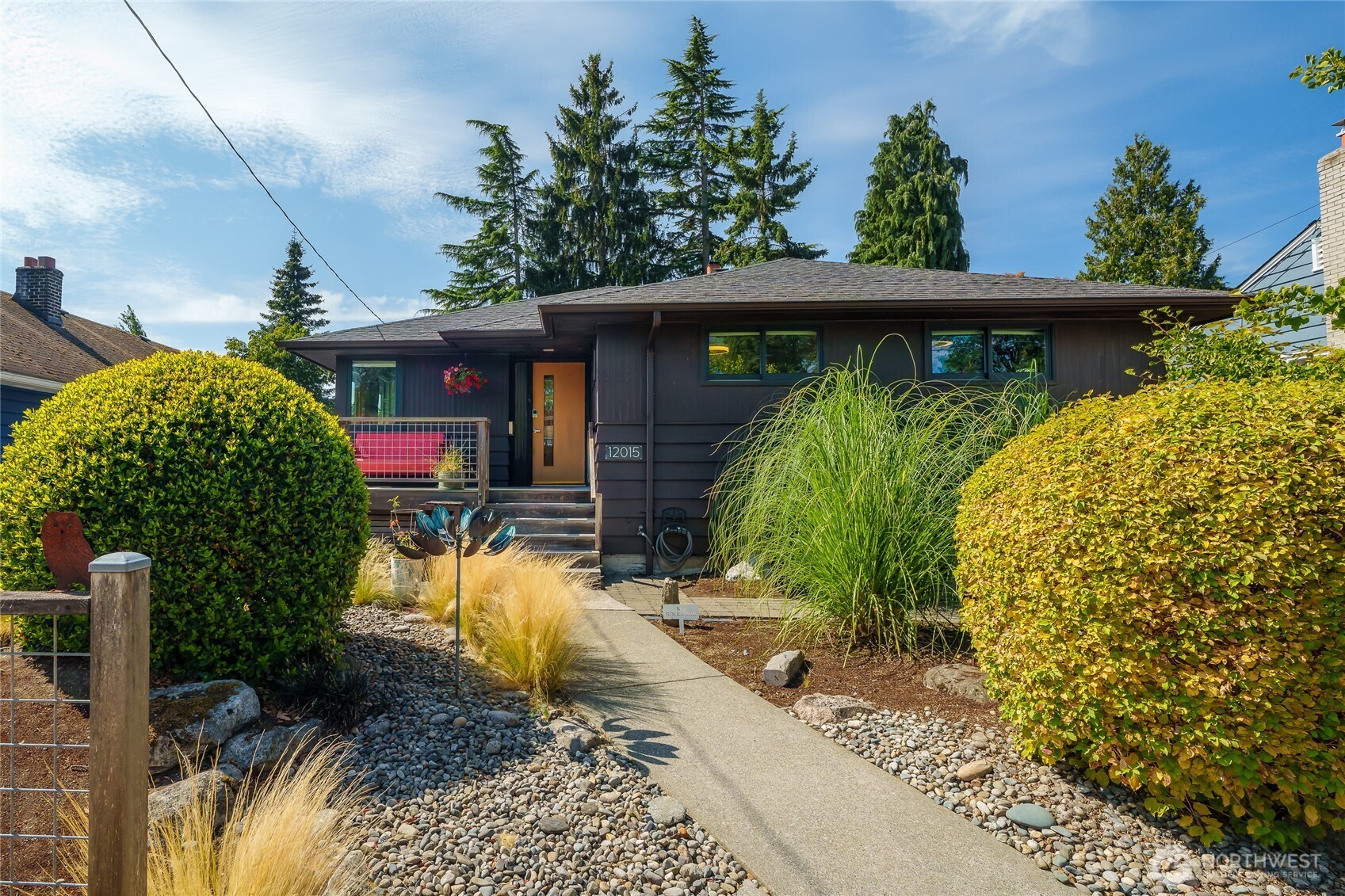 Mid-century charm meets thoughtful modern living in this wonderful 1952 home. From the beautifully landscaped front yard to the welcoming wraparound porch, there's a sense of character from the moment you arrive. Step inside and you'll find original mahogany paneling—a little wink to the home's era—alongside thoughtful updates and design-forward details throughout. Douglas fir-framed windows, an oversized picture window overlooking the backyard, and carefully chosen lighting bring warmth and personality to the living spaces, while French doors open to the deck and expansive backyard.    Downstairs, the daylight basement adds even more room to settle in, with a cozy family room made for movie nights and a dedicated hot tub room that's ready for the ultimate end-of-day unwind. Outside, the backyard feels like its own private escape. A custom-built, covered daybed tucked beneath the tall pines creates the perfect spot to curl up with a book, unwind, and listen to the birds. And for the tinkerer, fitness buff, or outdoor enthusiast, the shipping container offers flexible space for a workshop, gym, gear storage, or whatever your next project calls for.    With a new furnace, A/C and an updated bathroom featuring a deep soaking tub, this home strikes that sweet spot: the character and craftsmanship of its era, thoughtfully updated for the way we live today.