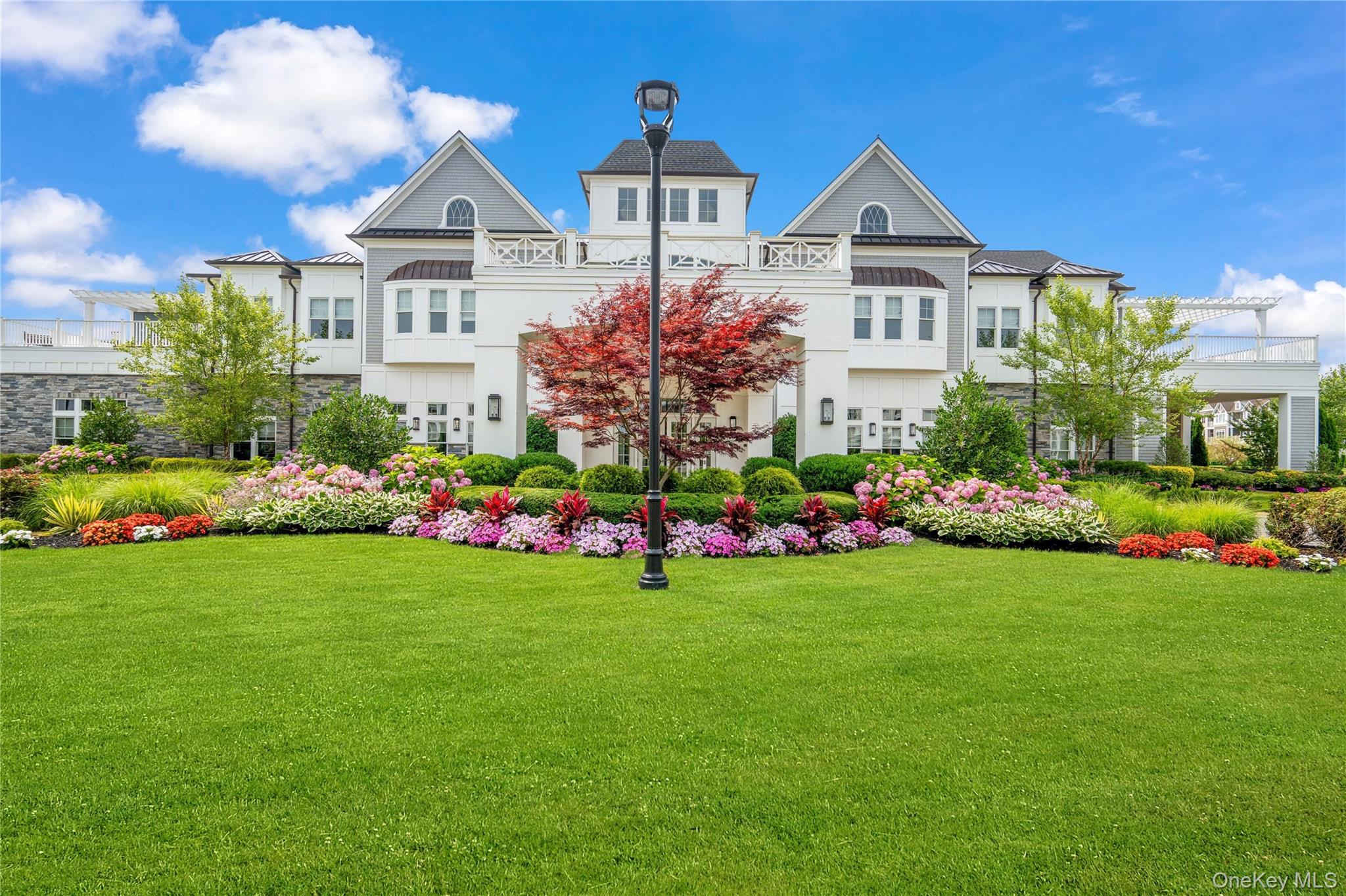 Welcome to Country Pointe Plainview, one of Long Island's premier 55+ gated communities, where sophisticated design meets an exceptional resort lifestyle. Ideally located just moments from the clubhouse, this beautifully appointed Greenbriar Villa offers the ease of main-level living with a sprawling, open floor plan and refined finishes throughout.Soaring cathedral ceilings, wood floors, custom windows, detailed moldings, and sun-drenched interiors create an atmosphere of timeless elegance. A private elevator and attached garage provide everyday convenience.Designed for both everyday living and gracious entertaining, the chef's kitchen is beautifully appointed with quartz countertops, an oversized center island, custom cabinetry extending to the ceiling with crown moldings, designer backsplash, premium stainless steel appliances, including a gas oven and microwave, and abundant storage. The kitchen flows seamlessly into the spacious great room, where a gas fireplace creates a warm focal point and sliding glass doors open to a private maintenance-free deck.The primary suite offers outfitted walk-in closets, a dressing area, and a luxurious ensuite bath featuring a double sink vanity, soaking tub, and frameless glass shower. A generously sized second bedroom, beautifully appointed hall bath, full laundry room with custom cabinetry, and custom shades complete this thoughtfully designed residence.Residents enjoy an unparalleled lifestyle centered around the spectacular 29,000 square-foot clubhouse, featuring 24-hour gated security, concierge services, a Director of Events, heated pool with poolside bar, fitness center, tennis, pickleball, bocce, EV charging stations, nearby Country Pointe Shops, and world-class golf courses just minutes away.An exceptional opportunity to enjoy luxury, convenience, and effortless living in one of Plainview's most sought-after gated communities.