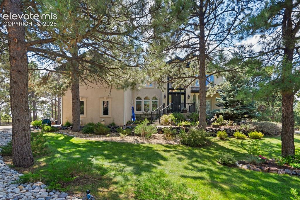 Impressive 2-Story Retreat on a private .76 Acre Lot!  Welcome to this exceptional 2-story Woodmoor home, offering the perfect blend of luxury, privacy, and functionality. Nestled on a beautifully landscaped .76-acre treed lot, this residence showcases immaculate curb appeal and thoughtfully designed outdoor spaces, including two decks, a stand-alone entertaining deck, and a cozy fire pit area—all ideal for relaxing or hosting gatherings.  Step inside to a majestic foyer with soaring ceilings and hardwood floors, setting the tone for the elegance throughout. The grand family room boasts floor-to-ceiling windows, flooding the space with natural light and serene views. The luxurious dining area flows seamlessly into the chef’s kitchen, which features an oversized uninterrupted island, stainless steel appliances, double ovens, a large gas range with custom hood, farm sink, quartz countertops, and decorative tile backsplash. The eat-in area walks out to a deck with a pergola, creating the perfect indoor-outdoor dining experience.  A main-level office/bedroom adds flexibility, while the convenient garage entrance off the kitchen enhances everyday functionality. Upstairs, retreat to the primary suite, complete with a fully remodeled spa-inspired 5-piece bathroom and an enormous walk-in closet with custom built-ins. Three additional bedrooms and 2 full bathrooms complete the upper level.  The finished basement expands your living space with a sprawling recreation room, pool table area, and access to a beautiful patio, perfect for entertaining. With central AC and countless updates, this home balances comfort and sophistication in every detail.  Don’t miss this rare opportunity to own a private, beautifully appointed home designed for both grand entertaining and everyday living in Monument!