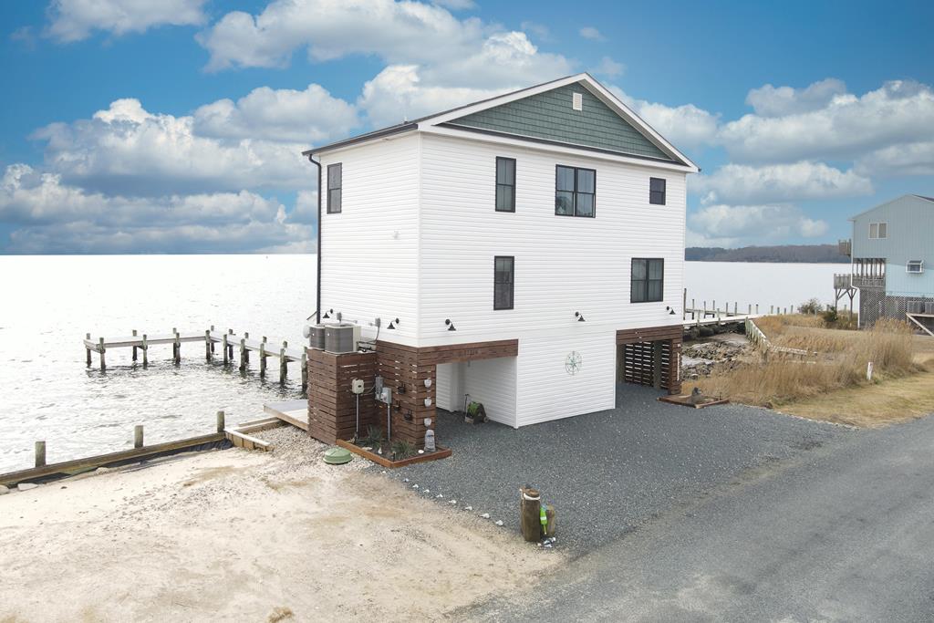 Tucked along the peaceful waters of Chincoteague Bay, this bayfront retreat invites you to slow down, breathe deep, and feel right at home. Offering 3 bedrooms and 2.5 baths, the contemporary design is balanced by thoughtful finishes, hardwood and Mexican tile floors, quartz countertops, vaulted ceilings, and an electric fireplace perfect for cozy evenings. Every bedroom enjoys a water view, gently connecting each space to the bay beyond. Step outside to your private dock, ideal for morning coffee, boating adventures, or watching the sun set over the water. Located in the Captain's Cove community, you'll enjoy pools, golf, a marina, fitness center, and 24/7 security. This isn't just a house, it's where your next chapter begins.  Call today for your private showing!