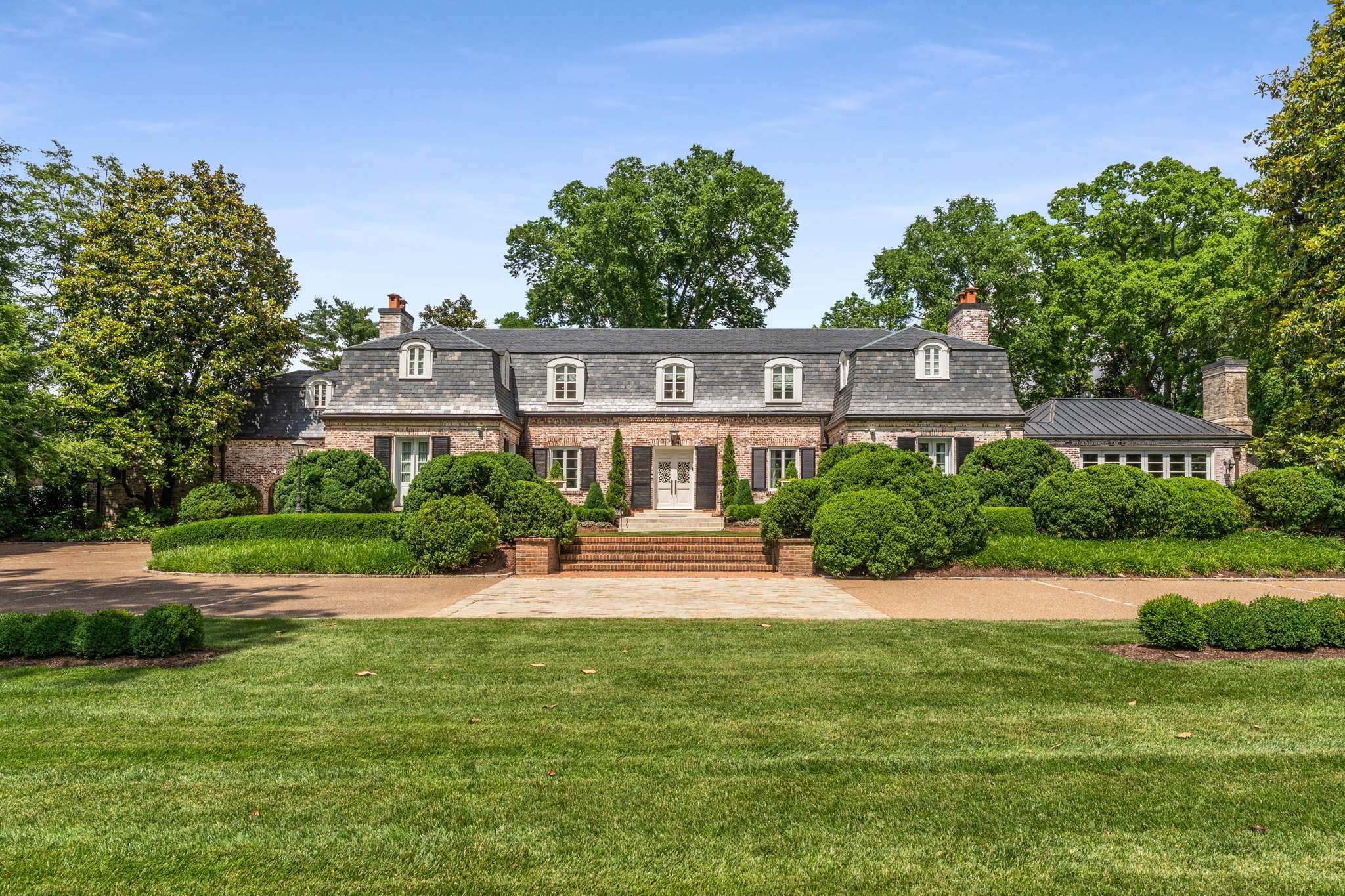 A refined and exceptionally upgraded residence that blends timeless architecture with modern luxury. Set on beautifully landscaped grounds, this elegant home offers a spacious, flexible layout with designer finishes, thoughtful details, and seamless indoor-outdoor flow.The main level features a stunning great room with folding glass doors that open to the private backyard, creating a resort-style living experience. The expanded kitchen is a standout, featuring a La Cornue range with rotisserie, Sub-Zero refrigerator and freezer, Wolf appliances, three dishwashers, custom cabinetry, and a dedicated bar area ideal for entertaining. A formal dining room, custom mudroom, and designer laundry area add both function and style. Upstairs, the primary suite offers a spa-like bath with heated floors, updated closets, and serene natural light. Additional bedrooms and bathrooms have been tastefully updated with quality materials and finishes. Outdoor features include a saltwater pool and hot tub, outdoor kitchen with built-in appliances, brick fireplace, cold plunge, and multiple lounge areas. The pool house offers a full bath and media space. A private guest house and two climate controlled garages each with full bathrooms—add flexibility and value.This is luxury living with every detail carefully considered.