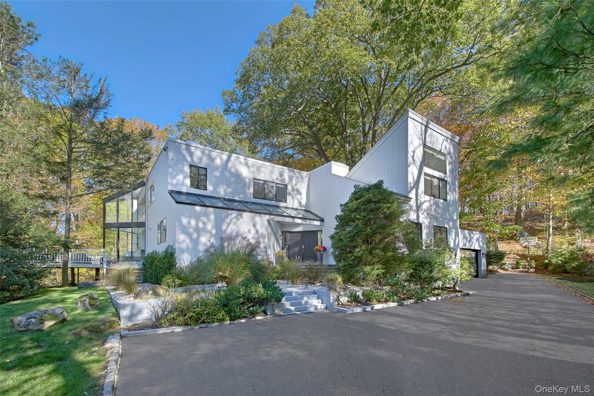 Experience modern luxury and timeless sophistication in this stunning contemporary, beautifully sited on over an acre of park-like property in Chappaqua’s sought-after Whippoorwill neighborhood. Set on a quiet cul-de-sac with a majestic approach, this home is surrounded by mature trees and lush landscaping, creating a private oasis with level play areas and serene natural views backing to a protected nature preserve. This dramatic residence features soaring ceilings, expansive windows, gorgeous hardwood floors and sophisticated modern design throughout. A bold double-door entry opens to a sun-drenched foyer and gallery-like living spaces. The vaulted dining room with floor-to-ceiling windows flows seamlessly into an oversized living room with a fireplace and sliders to expansive wraparound decks—perfect for indoor/outdoor entertaining. The beautiful chef’s kitchen showcases stainless steel appliances, custom cabinetry, and a breakfast area with sliders for effortless alfresco dining.  The main level also includes a spacious home office (or playroom) with a second fireplace, a guest bedroom/office, full bath, laundry area, and an attached two-car garage. Upstairs, the primary suite offers a fireplace, private balcony, dual walk-in closets, and an ensuite bath. Three additional bedrooms include one with an en-suite bath and two sharing a stylishly updated hall bath. The walk-out lower level provides great space for recreationa and storage. Offering a rare combination of architectural drama, flexible living space, and resort-like grounds, this exceptional home delivers the best of modern living in a peaceful Whippoorwill setting within the award-winning Chappaqua School District. AO 11/1/25