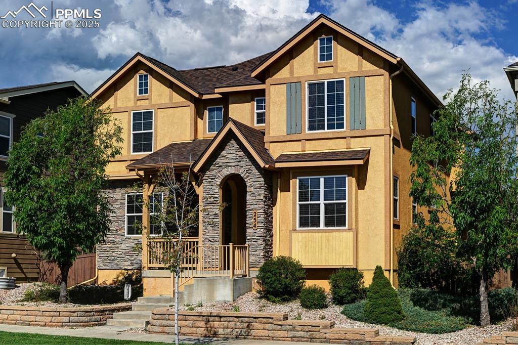 Welcome to this beautifully crafted modern Tudor home that effortlessly blends old-world charm with contemporary luxury. Nestled in the idyllic Gold Hill Mesa neighborhood, this property offers exceptional curb appeal with decorative half-timbering on stucco exterior, striking stone accents, arched entry & inviting front porch—perfectly complemented by a mountain backdrop to the west. Inside, you’re greeted by rustic maple wood floors leading into a chef-inspired kitchen, with rich birch cabinetry extending along the entire wall, durable solid-surface countertops, stainless steel wall ovens & refrigerator & a glass top cook top. A spacious curved island with bar seating adds both elegance & functionality. Adjacent living room features cozy gas fireplace & seamlessly flows into covered patio & fenced backyard. Landscaping offers mature trees & lush turf, ensuring a green, beautiful space without hassle. Whether entertaining, enjoying a quiet afternoon, or letting kids & pets play freely, this outdoor area offers year-round enjoyment in complete privacy. Main-level office with classic French doors provides ideal space for remote work or study. Efficient mudroom at garage entry brings daily convenience & organization to busy lifestyles. Upstairs owner's suite is a true retreat, featuring tray ceiling, dual closets, spa-inspired bath with dual vanities, soaking tub & separate shower. Step out onto private upper-level deck & immerse yourself in the peaceful surroundings with gorgeous mountain views & breathtaking sunsets. 3 additional BRs & a full bath for family or guests. Fully finished basement includes large family room, sleek wet bar with cabinetry & beverage fridge, 4th BR & additional full bath. Enjoy front yard maintenance, trash pickup, fitness & community center. Convenient to schools, shopping, dining & entertainment, with quick access to Fort Carson, Schriever AFB, Peterson AFB, and the Air Force Academy, and all that Westside living has to offer!