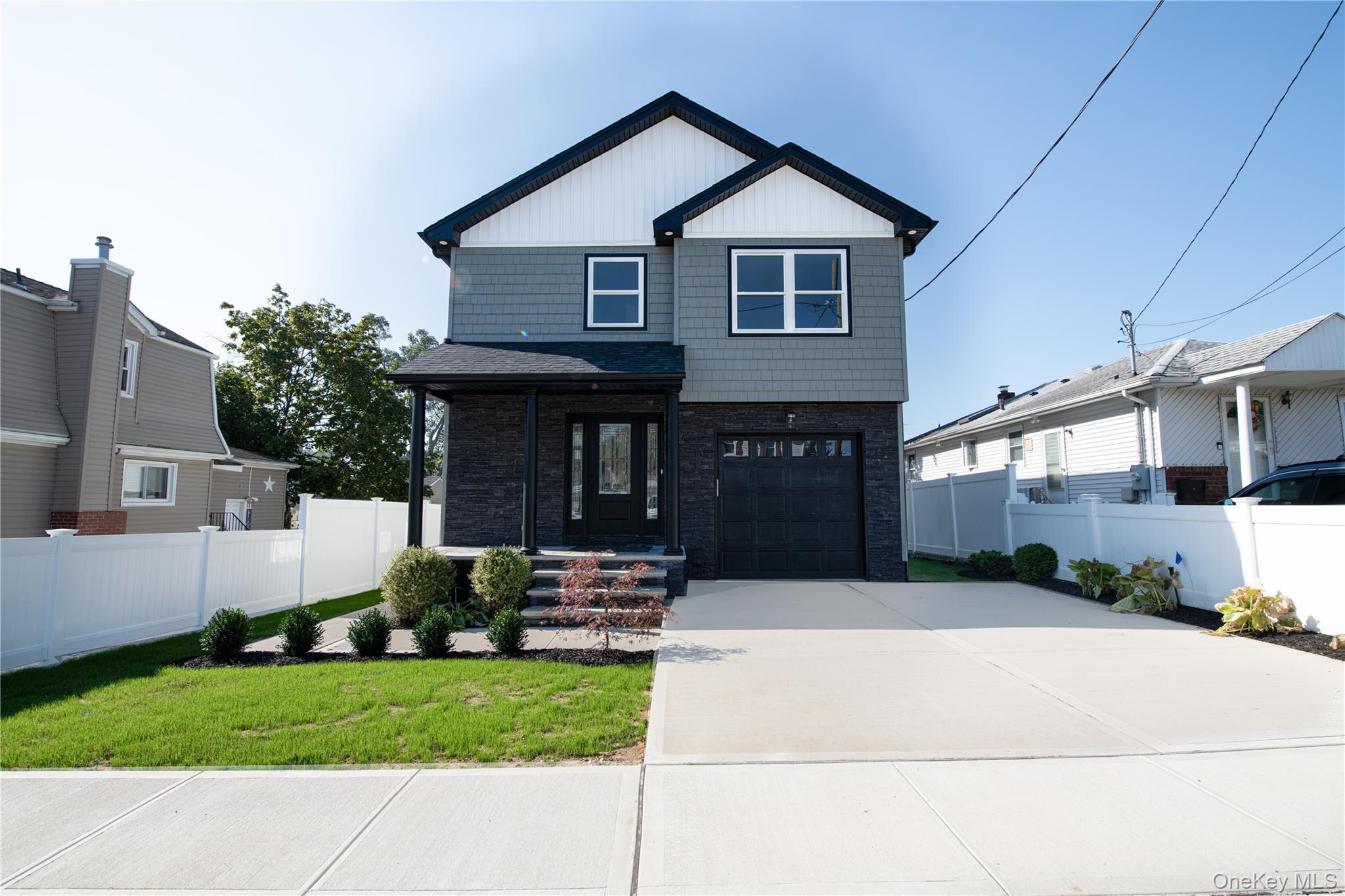 Welcome to 179 Hillsboro Avenue, a brand-new 4-bedroom, 2.5-bathroom home in Elmont—move-in ready with quality finishes throughout.This striking two-story home features dark gray siding, a sleek black attached garage door, and a covered front entry with stone accent detailing. White vinyl fencing provides privacy, while a concrete driveway and neatly maintained front yard complete the polished, contemporary look.Inside, the first floor offers 9-foot ceilings, hardwood floors, and an open-concept layout. The living room flows into a formal dining area, while the kitchen showcases white cabinetry with black hardware, quartz countertops, Samsung appliances, and sliding glass doors leading to a private fenced backyard.Upstairs, the primary suite includes oversized windows, a walk-in closet, and a full bath with skylight, glass-enclosed shower, and marble-style finishes. Three additional bedrooms share a modern full bath. Second-floor laundry with Samsung washer and dryer included.Additional highlights: powder room with black accents and marble-look flooring, full basement with 9-foot ceilings and egress window, attached garage, spray foam insulation, central A/C, and recessed lighting throughout.Interior photos have been virtually staged to showcase the home's potential.