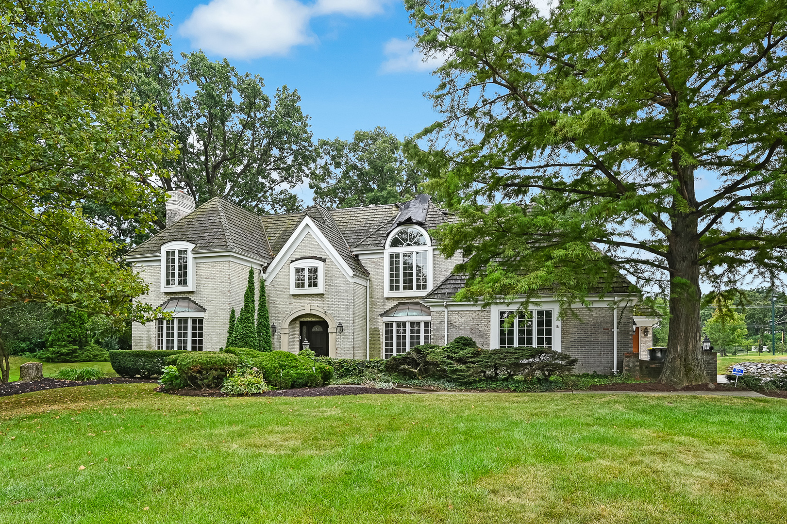 Tucked away on a sprawling .79-acre lot within the prestigious Midwest Club, this property presents a rare opportunity to either renovate the existing structure or build the custom estate of your dreams. The current home features a thoughtful layout with four bedrooms-each with its own ensuite bath-along with formal living and dining rooms, a first floor office, a three-car attached garage, and a massive unfinished lower level ready for your personal touch. Living in The Midwest Club is about more than just a home; it's about a lifestyle defined by luxury and ease. The community is anchored by a clubhouse, an outdoor swimming pool and hot tub, tennis and pickleball courts, and a playground. From the moment you pass through the majestic entry-complete with reclaimed Chicago pavers and an English cottage-style gatehouse-the attention to detail is clear. Seven scenic ponds, seasonal waterfalls, and meticulously maintained green spaces create a stunning backdrop for daily life, while the on-site management team fosters a vibrant community spirit through seasonal activities and holiday gatherings. Privacy and convenience go hand-in-hand here. The main entrance is managed by 24-hour on-site security, providing total peace of mind. Plus, the location is hard to beat, offering quick access to major expressways, airports, premier shopping, and an incredible variety of fine dining. Adding to the appeal, this property is situated within the highly acclaimed Butler Elementary and Hinsdale Central High School districts. Whether you're looking to polish a diamond in the rough or start fresh on a premier lot, this is your chance to join one of the area's most sought-after communities.