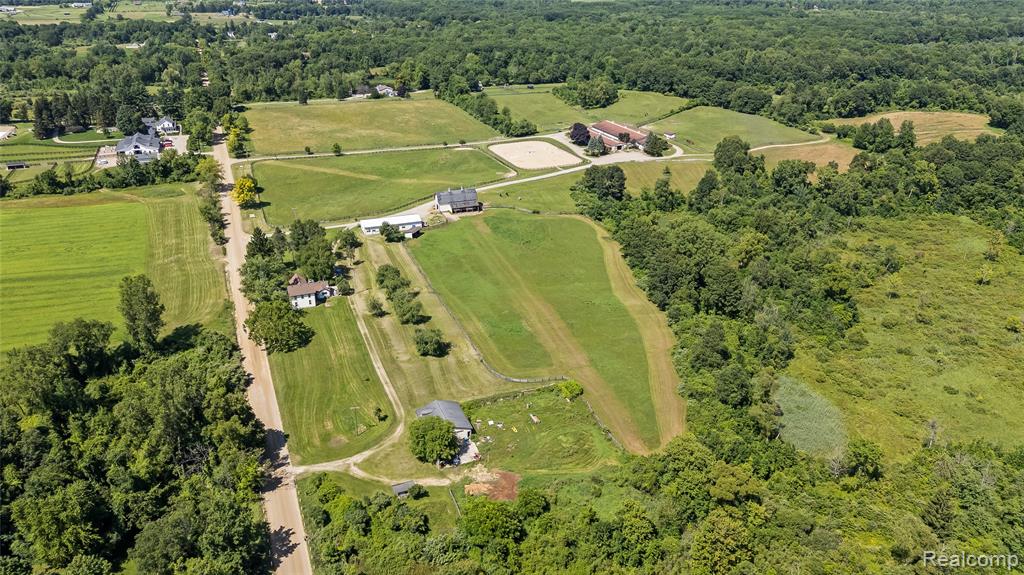Seize the opportunity to acquire the well known 116 acre Interlaken Farm. Perfectly situated in the Metamora Hunt Country in Oxford, this grand equine facility is on one of the largest parcels of land currently available in Oakland County. Experience the diverse topography of this amazing piece of land with rolling meadows, 7 pastures, a small paddock, woods, trails and frontage on a small lake. Approximately 20 acres is currently in hay. Through the front entrance of the main barn is a large heated tackroom and office, both have dark stained tongue and groove paneling and picture windows overlooking the 150x240 outdoor arena and front pasture. A 1/2 bath and lounge complete this area. The 12 ft. main aisleway has 25 matted stalls (12X12), a double grooming area, wash rack with hot and cold water, a laundry room / workshop and feed room. The attached indoor arena is 70x180 and has an observation room that is currently being utilized as an apartment. Barn #2 (22x65) once a historic grainery was converted to a 5 stall barn with overhead hay storage and a 14x48 attached run-in shed. Barn #3 (40x85) is used for equipment storage has a workshop.  Barn #4 (44x45), next to the 10x9 potting shed is used for storage. The 100+ year old farmhouse has 4 bedrooms and 2 full baths. A bright 4 season room overlooks the pasture and small apple orchard and leads to country kitchen and main floor laundry room. Some of the original hardwood floors remain. The farm has 2 wells, 2 septic's and is zoned agricultural. So much potential, bring your creativity, update this amazing property and make it your own. 24 hr. notice to show. All showings shall be accompanied by the listing agent.