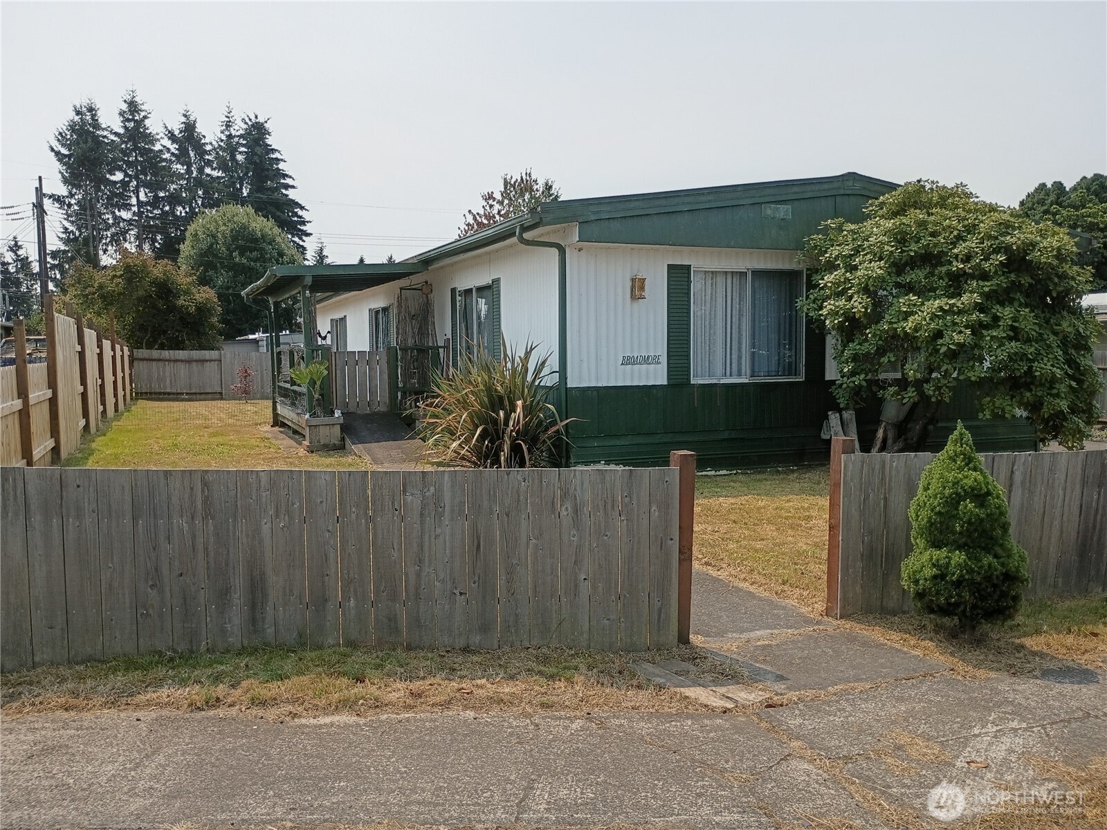 Enjoy the largest lot in the park and plenty of room to spread out in this spacious three-bedroom home! A large living room welcomes abundant natural light, while the dining room offers built-in cabinetry. A separate space off the kitchen provides flexibility for a second dining area or additional living space. The primary bedroom includes a private bath. The low-maintenance yard is fenced except at the driveway entrance. A covered front porch, carport, and storage shed add convenience. Updates include new plumbing and underbelly covering. The torch-down roof was installed approximately seven years ago, with no leaks reported. The older furnace continues to operate well, and existing ductwork may accommodate a future heat pump; buyer to verify. Located approximately 20 minutes from grocery stores, hospitals, and dining, and about an hour from the beach, mountains, or city amenities. This is a 55+ community with current space rent of $340 per month, excluding utilities. Park approval is required; buyers under 55 should confirm eligibility directly with park management. Cash purchase or seller financing available.