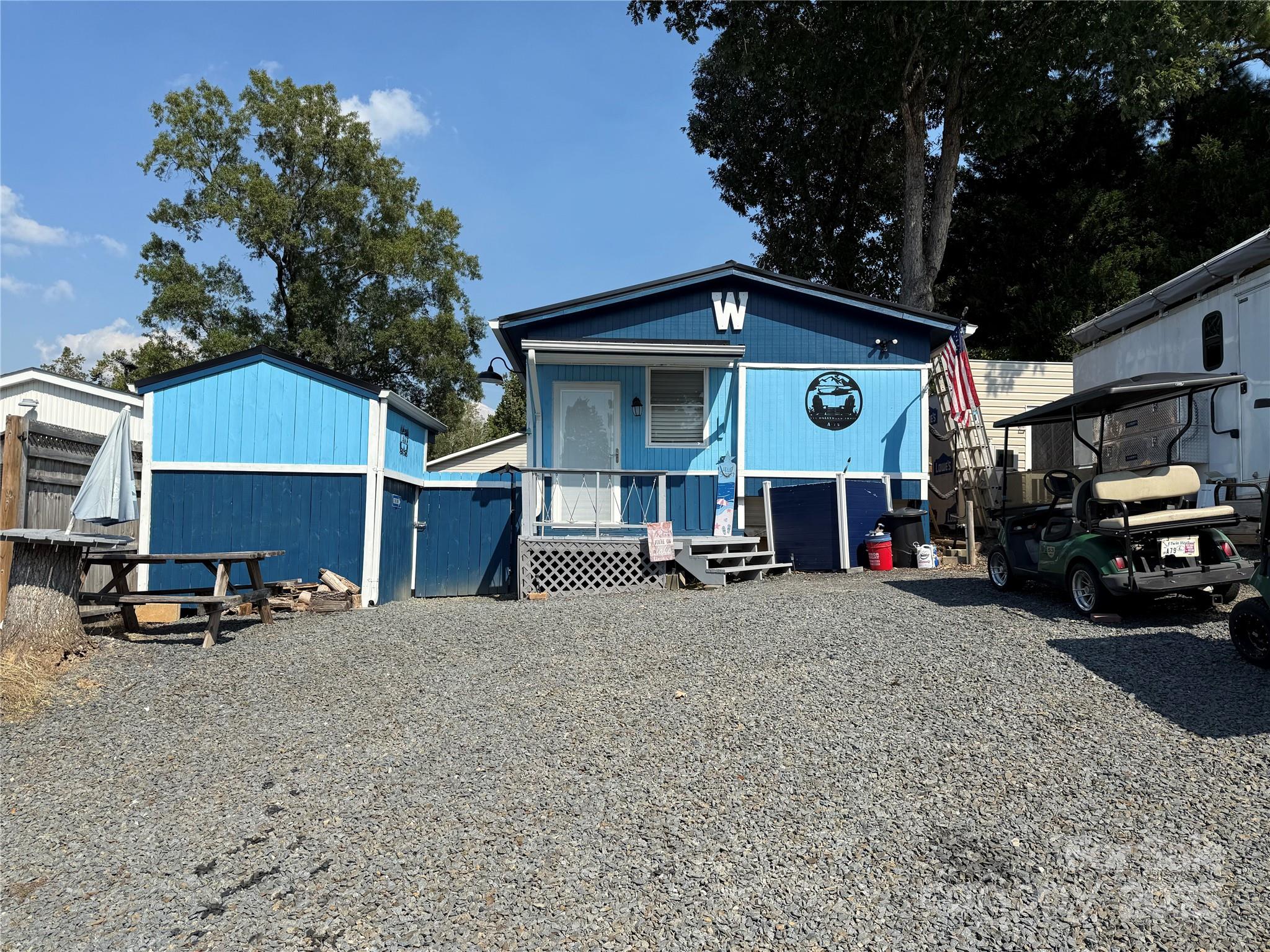 Welcome to this unique unit here in the park. This a 2 bedroom, 2 1/2 baths unit with a fabulous outdoor kitchen setup and a second sleeping/bathroom space. Included in the outdoor kitchen -  Blackstone Gas Griddle, Blackstone Prep Area, covered with elec and fan. Move over to the covered bar side and you have 4 stools, a beverage refrigerator, Microwave, Ninja Foodie Grill, Panini Maker, Oster French Door Oven. Power and a TV are already there. There is a covered swing, fenced yard for the pets and a pet washing station. Inside is a great living room freshly painted with new flooring. Most furnishing to remain. U shaped couch makes a comfortable queen bed. The kitchen has an ice maker, great counter space and brand new flooring. Metal roof is 1 year old. Propane Hot Water on Demand 2 years old. 2 Window units for AC and a wall mounted propane heater for your heat source. Access door just added to the side of unit for the convenience of letting the dogs out into the fenced area. Full bath with walk in shower. Storage or Sleeping loft above main bath room. Double size bed and 1/2 bath on the camper side. Out back is double bunks, a full bath and enough room to add a washer and dryer if desired. Portable A/C and fan.
Come and see if this is your "Happy Place" here in the Park. No title to camper, Bill of Sale will be provided. 
There are 2 Yamaha 2011 golf carts available for Alum wheels $4k, black wheels $3k. 
All buyers must be with a realtor to gain access to the community.