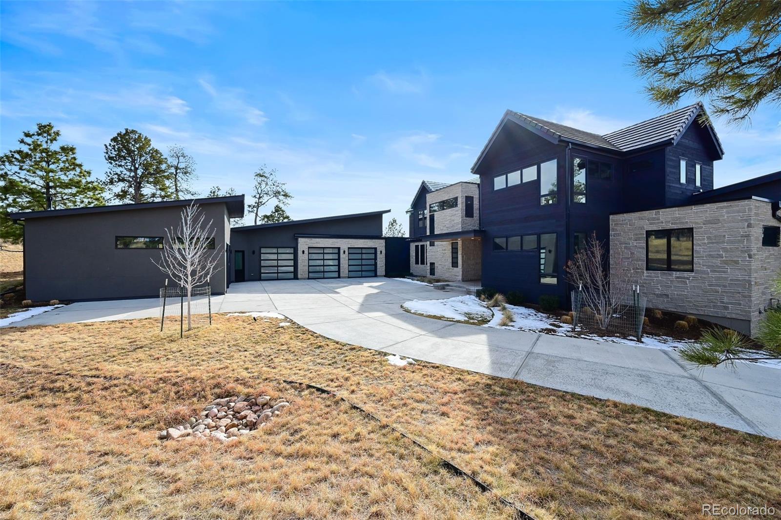 This extraordinary custom residence blends modern architecture, luxury design, and resort-style living on a breathtaking, private setting. Thoughtfully crafted with soaring ceilings, wide-plank hardwood floors, and walls of windows, the home is filled with natural light and showcases stunning mountain and acreage views throughout. The heart of the home is an open-concept living space anchored by a chef's kitchen with bold soapstone double islands, premium appliances, a cleverly concealed behind seamless cabinet front walk-in pantry, and seamless flow into elegant dining and gathering areas-perfect for both everyday living and grand entertaining. The primary suite is a true retreat, offering a serene bedroom, spa-inspired bath with soaking tub and dual vanities, a gorgeous walk-in closet, and a convenient main-level laundry just steps away. Additional bedrooms are spacious and beautifully appointed, providing comfort and flexibility for family and guests. The lower level is an entertainer's dream, featuring a full custom bar, expansive recreation space, media area, and a private guest suite with an attached designer bath, coffee bar with beverage refrigerator-ideal for visitors or multi-generational living. Outdoor living rivals that of a luxury resort with a covered patio complete with built-in grill, covered dining area, multiple seating zones, firepit and panoramic views. The grounds are equally impressive, offering a sports court, pool area, hot tub, terraced patios, and tranquil spaces to unwind and take in Colorado's natural beauty. A gated dog run, stunning landscaping, and expansive 5- car heated garage complete this exceptional property. This is more than a home-it's a lifestyle of elegance, comfort, and unforgettable living.