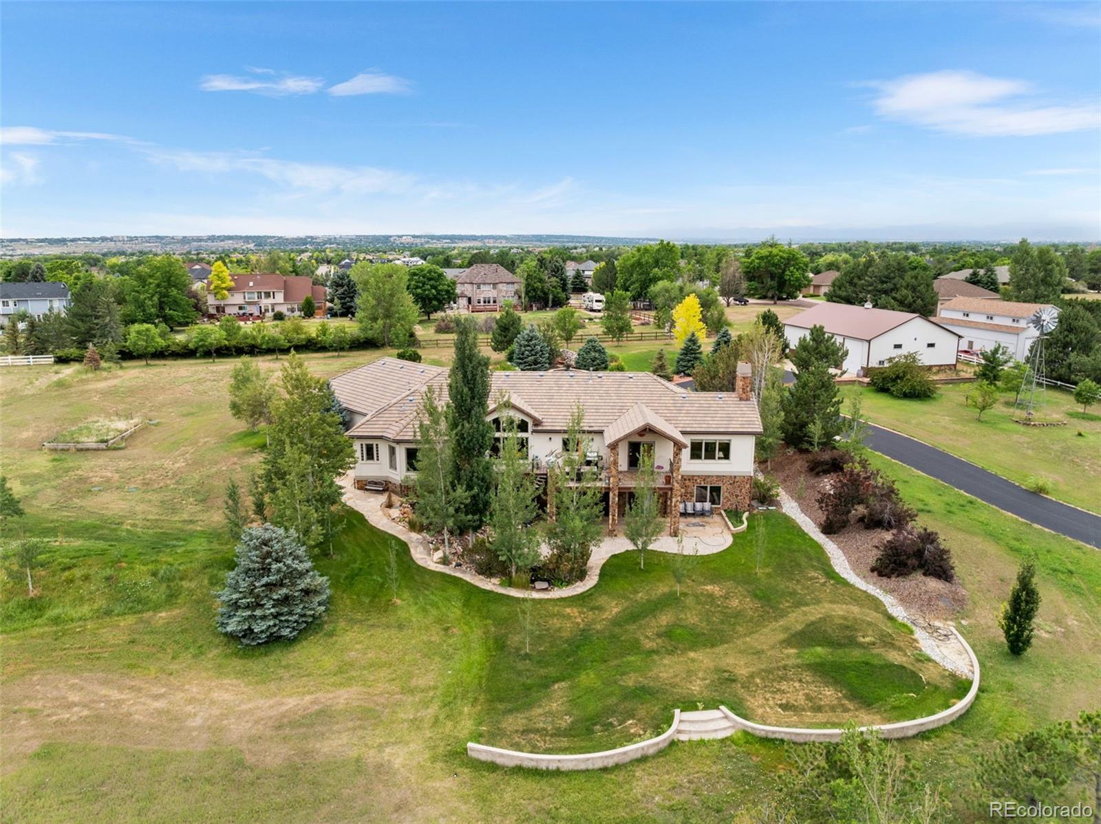 This CUSTOM HOME is surrounded by mature trees and set on 2.5 private acres, offering refined comfort, breathtaking views, and a heated 2,400 sq ft barn with an RV slip—ideal for storage, hobbies, or additional space. Inside, you'll find 4 bedrooms, 4 baths, and a dedicated office space. The 4th bedroom is perfect for a home gym setup.  Rich stone and woodwork carry throughout the home, showcasing true craftsmanship and timeless character. The formal dining room features a tray ceiling with Italian-inspired detail, while the gourmet kitchen stands out with a gas cooktop, high-end appliances, and dual sinks—perfect for cooking and entertaining. The living room captures sweeping mountain views, anchored by a detailed stone fireplace and accented by stained glass windows that fill the space with soft, natural light. A second stone fireplace adds warmth to the cozy great room. The main-floor primary suite is a true retreat, with stunning views, a 5-piece skylit bath, and a spacious walk-in closet. The main-floor laundry room, complete with utility sink, adds function to the thoughtful layout. The walk-out basement expands your living space with a wet bar, wine fridge, and dishwasher—ideal for gatherings and relaxed evenings. Outside, enjoy the open land, chicken coop, and practical features including well, septic, and full irrigation. Whether you're taking in the sunsets from the back deck or making use of the barn, this home offers a perfect blend of elegance, space, and functionality.