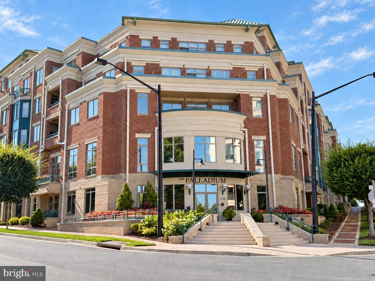 Perched above downtown McLean at The Palladium, this rarely available two bedroom, two and a half bath corner unit with over 2300sf offers something special: a home filled with abundant light and genuine space. With soaring 9+ ft ceilings, an expansive great-room layout, and light pouring in from nearly every angle, the home lives less like a condo and more like a single-level residence— ideal for anyone trading multiple floors for the ease of one beautifully proportioned level and the lock and leave lifestyle you desire. A private, fully enclosed two-car garage within the building's secure parking level adds a rare layer of convenience and storage options. Wood floors, crown molding, and recessed lighting run throughout, setting a polished tone from the tray-ceiling foyer onward. The living room spans nearly 18 by 18 feet, its symphony of windows flooding the room with light, while an electric fireplace adds warmth. The dining room, sized for real entertaining, pairs a chandelier and chair railing with built-in cabinetry and more windows. The kitchen is equally gracious— granite counters, ceiling height cabinetry with undercabinet lighting, full-height tile backsplash, and a full suite of stainless steel appliances, including a KitchenAid refrigerator, Bosch dishwasher, and five-burner gas cooktop.  A sliding glass door with transom window opens onto the private balcony overlooking the community's impressive water fountain and gathering space. At over 20 by 32 feet, the primary suite is a retreat in its own right, with a large walk-in closet and an ensuite bath featuring a double vanity with granite counters, soaking tub, and frameless walk-in shower with floor-to-ceiling tile. The second bedroom is just as thoughtfully appointed, with walk-in and reach-in closets and its own full ensuite bath. French doors to a private office or den, a powder room and dedicated laundry room with LG and Whirlpool machines and a beverage refrigerator complete the home. Beyond the residence, the sought after Palladium delivers full-service living — concierge, a fitness center, a club/party room with library and lounge, conference room, and an expansive landscaped courtyard with grills and outdoor seating, and is right in downtown McLean where specialty shops, boutique grocers, multiple restaurants, and coffee shops are all within reach. Tysons with Capital One Center, Tysons Galleria, the Ritz Carlton, and other world class shopping, dining and entertainment is minutes away.  Reagan National Airport is 12 miles, and Dulles International Airport is 14.5 miles. Welcome home!