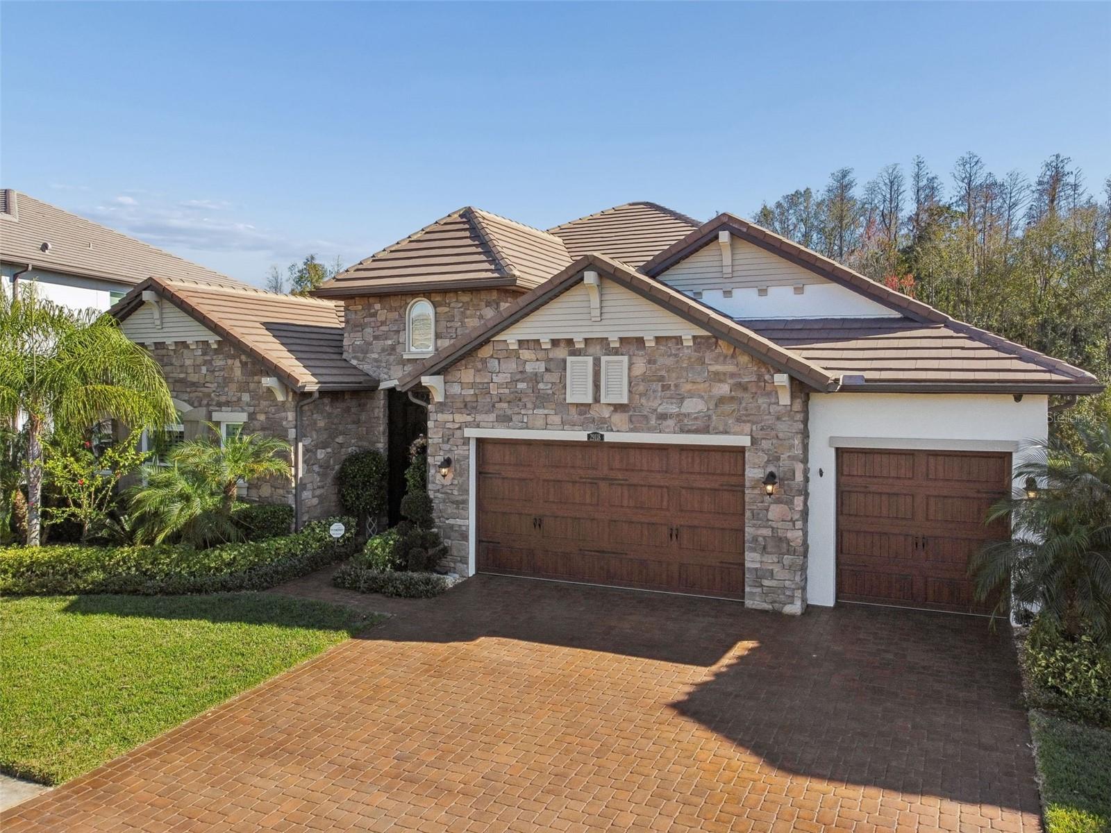 Welcome to 29118 Picana Lane, a masterfully built home offering modern sophistication paired with thoughtful custom upgrades throughout. Built in 2019 by WCI, this stunning residence is tucked in the prestigious gated haven of Matera in Estancia at Wiregrass. From the moment you arrive, you’ll appreciate approximately $200,000 spent in builder upgrades along with an additional $170,000 spent in elegant custom enhancements. The functional open floor plan features high ceilings throughout and a spacious chef’s kitchen complete with built-in double Dutch convection ovens, a walk-in pantry and ample workspace. Additional highlights include a formal dining room with dry bar, two bonus rooms, one of which is oversized on the second floor, a huge living room that opens to a screened-in lanai, and four sizable bedrooms offering privacy and comfort. The centrally located laundry room, generously sized baths, and immense storage and closet space throughout the home further enhance everyday living. The three-car garage includes a Tesla charger, and the driveway offers three additional parking spaces, ideal for guests. Outside, the home continues to impress with professionally manicured landscaping, stylish hardscapes, and a massive screened-in lanai featuring a custom-designed heated saltwater pool with sun shelf and spa. A custom planter feature within the lanai provides a beautiful backdrop to the pool, while the outdoor grill connected to natural gas, vinyl-fenced yard, and oversized lot backing to a wooded preserve offer privacy and exceptional outdoor living. Additional builder upgrades and custom features include exterior stone by stone facing, interior stone wall covering, tile roof, paver brick driveway and lanai, hurricane-rated windows, house doors and garage doors, whole-house water purification system, custom built-in closet organizers, 6-foot soaking tub with jets, interior and exterior custom lighting fixtures, California electric blinds, whole-house blue tube air purifier, custom wrought iron stair railings and front gate, stone kitchen and bath countertops, kitchen and bath custom cabinetry,  built-in whole-house exterior wall pest control system and a high quality security system with cameras. There are many additional custom upgrades that are not listed. Residents enjoy access to the community clubhouse, swimming pool, tennis courts, pickleball courts, basketball courts, playgrounds, dog park and fitness center. Estancia at Wiregrass is more than a neighborhood, it’s a lifestyle, offering Wesley Chapel’s premier planned community, resort-style amenities, top-rated schools and an unbeatable location just minutes from Wiregrass Mall, The Grove, fine dining, hospitals and major commuter routes. This exceptional home has so much to offer, is priced to sell and is a must-see. Call today to schedule your private showing.