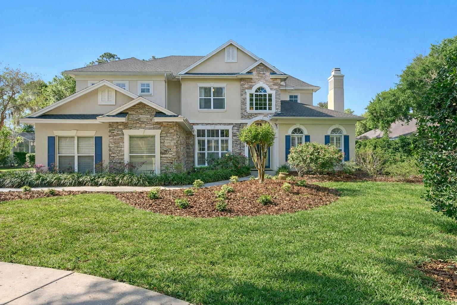 Tucked within an exclusive gated enclave inside the prestigious golf course community of Hunter’s Green, this exceptional Hannah Bartoletta residence offers a rare blend of refined craftsmanship, modern upgrades, and breathtaking water and golf course views. Positioned on a tranquil homesite within an intimate village of just twelve custom homes, the setting delivers both privacy and presence from the moment you arrive.Inside, a grand foyer framed by architectural columns opens to beautifully appointed formal living and dining spaces, where rich wood flooring, detailed wall molding, plantation shutters, and thick crown molding create a warm yet sophisticated atmosphere. The heart of the home has been completely transformed by a full-scale kitchen and butler’s pantry renovation, now showcasing a designer aesthetic paired with high-end functionality. Crisp shaker cabinetry, striking quartz countertops, large center island, designer pendant lighting, and upgraded appliances anchor the space. The kitchen seamlessly connects to a spacious casual dining area and inviting family room, where soaring ceilings and expansive windows frame serene outdoor views.The primary suite is thoughtfully positioned on the main level, offering a private retreat with direct access to the outdoor living space.  Additional living spaces include a dedicated office downstairs, while the upper level features four bedrooms and two full baths, offering excellent flexibility for everyday living. One of the bedrooms does not include a closet and may also serve beautifully as a bonus room, media space, or flex area to suit your needs.Step outside to an expansive lanai designed to take full advantage of the picturesque surroundings. The outdoor living area features a sparkling pool and spa, all overlooking peaceful water and manicured golf course views that create a truly resort-style experience.Extensive capital improvements enhance both value and peace of mind, including a full roof replacement (2021), updated HVAC systems (2022), renovated kitchen and butler's pantry (2019), pool deck resurfacing (2026), and numerous additional upgrades completed over time totaling nearly $285,000.Hunter’s Green is a guard-gated community that continues to be a top choice for buyers relocating to the Tampa Bay area, thanks to its prime location, exceptional quality of life, and access to highly rated schools. At the heart of the community is Hunter’s Green Golf and Country Club, one of the premier private clubs in the Southeast, featuring a championship Tom Fazio–designed golf course, an active tennis program, and resort-style amenities. Ideally located just minutes from I-75, shopping, restaurants, recreation, Flatwoods Park trails, and top medical facilities including AdventHealth, the VA, and Moffitt Cancer Center, everything you need is right at your fingertips.