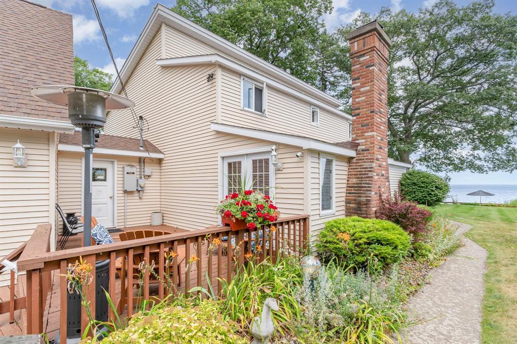 Nestled on quiet, tree-lined streets in a peaceful, walkable neighborhood, this stunning two-story home offers 65 feet of pristine Lake Huron frontage and exceptional waterfront living. With approximately 3,300 sq. ft. and a 5-car garage, the home provides ample space for entertaining, privacy, and intimate relaxation. Expansive lake views showcase passing freighters and fishermen at work, with endless opportunities to enjoy kayaking, paddleboarding, canoeing, or leisurely strolls along the beach. Inside, timeless charm blends seamlessly with modern updates. The home features two primary suites with private baths with one on the main floor and one on upper level with each offering breathtaking lake views. Three additional bedrooms and a main bath upstairs provide plenty of space for family and guests. The main level also includes a welcoming living room with gas fireplace, a cozy family room with wood-burning fireplace, and a chefs kitchen with sweeping bay views. Multiple seating areas throughout the home create a perfect balance of comfort, privacy, and style. Thoughtful features include an oversized Kitchen Aid refrigerator, Dacor commercial gas range, kitchen prep sink, custom kitchen cabinets, zoned heating, a whole-house Generac generator, a newer gas hot water heater, and a 15-year-old seawall. Outdoors, the deep, professionally landscaped lot with irrigation system leads to a sprawling lakefront deck, a unique boathouse, and a garage with potential for an upper-level bonus room. This home embodies classic Lake Huron waterfront living in the desirable Huron Oaks subdivision where modern conveniences, breathtaking scenery, and endless recreational opportunities come together.
