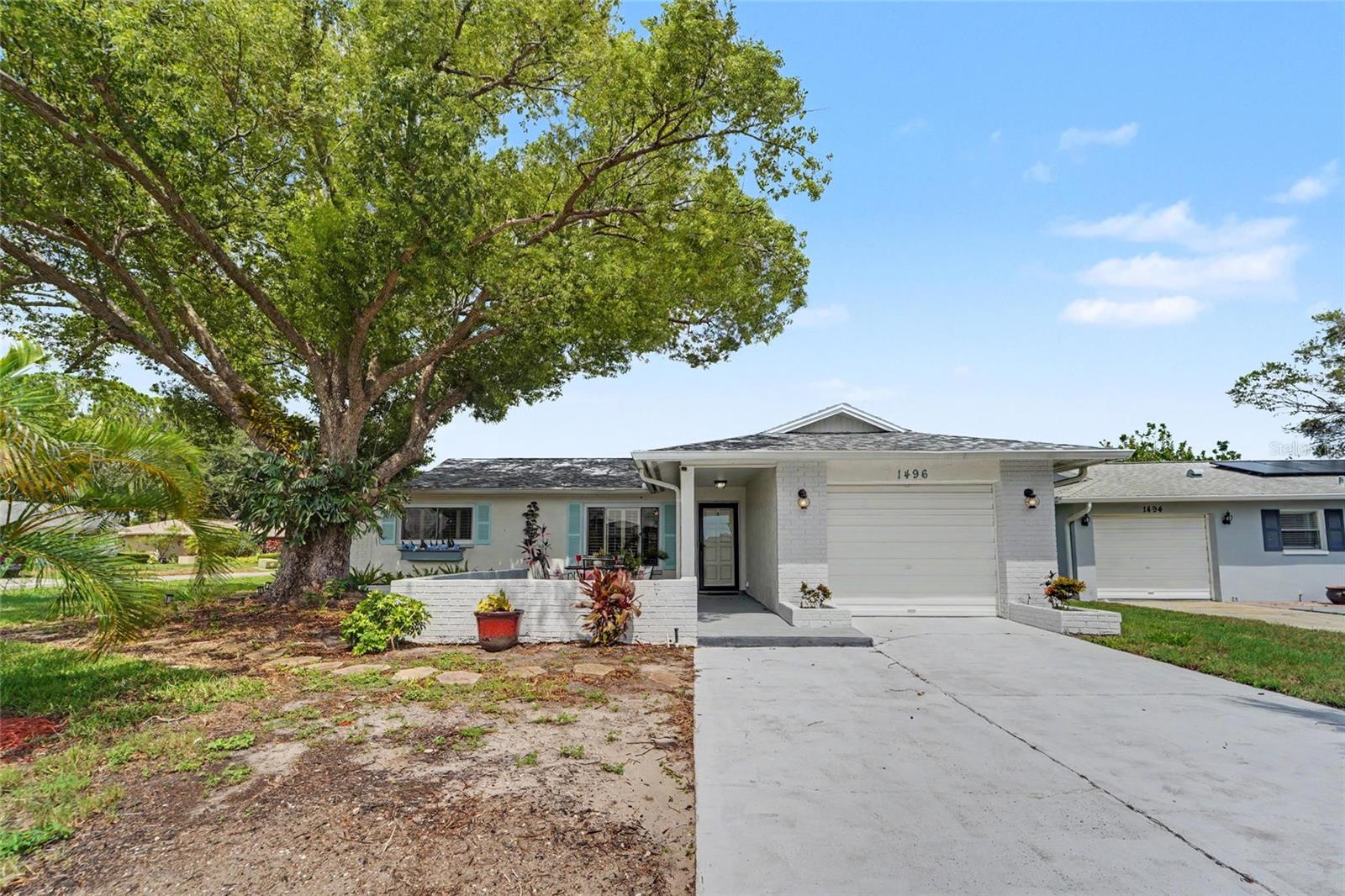 Welcome to your own slice of Florida paradise in the highly sought-after 55+ community of Highland Lakes! This delightful two-bedroom, two-bath cottage perfectly blends comfort, character, and an easygoing coastal lifestyle. From the moment you arrive, you'll be charmed by the inviting front courtyard, where a majestic live oak provides cool shade over a spacious patio framed by a low brick wall—the perfect spot to enjoy your morning coffee, visit with neighbors, or unwind with an evening glass of wine.Inside, the home offers a bright, welcoming atmosphere, including plantation shutters on the windows and with luxury vinyl plank flooring throughout the living areas and bedrooms, complemented by tile flooring in the kitchen and baths. The updated kitchen features timeless white cabinets, Corian countertops, stainless steel appliances, and plenty of workspace for everyday living or entertaining.The beautifully remodeled main bathroom showcases a sleek walk-in shower, modern floating vanity, and stylish contemporary finishes, creating a spa-like retreat that elevates the home's appeal.One of this home's most enjoyable features is the spacious enclosed Florida room, complete with its own mini-split heating and cooling system, allowing you to enjoy this light-filled space comfortably year-round. Whether you envision it as a reading room, hobby space, home office, or additional gathering area, it quickly becomes one of the favorite rooms in the house. Just outside, the covered patio provides another inviting place to grill, entertain, or simply relax while overlooking the beautifully situated corner lot.Practical updates provide peace of mind, including a **2023 Carrier HVAC system** and a **2021 roof (with hurricane clips**, allowing you to spend less time worrying about maintenance and more time enjoying everything this wonderful community has to offer. And in your spacious 1-car garage, you'll find the golf cart, which comes with the house!And what a community it is! Highland Lakes is one of Palm Harbor's premier active-adult neighborhoods, offering an unmatched collection of amenities included with your HOA membership. Residents enjoy unlimited golf on three private executive courses, two heated swimming pools, tennis and pickleball courts, a vibrant clubhouse with dozens of clubs and social activities, arts and crafts studios, a fitness program, RV and boat storage (subject to availability), and the unique Lake Tarpon Lodge. From the lodge, residents can enjoy complimentary pontoon boat cruises across beautiful Lake Tarpon—including leisurely 90-minute excursions with a stop at the popular Tarpon Turtle Waterfront Grill for lunch or dinner. It's a lifestyle unlike any other in the area.Ideally located near Gulf beaches, the Pinellas Trail, shopping, dining, medical facilities, airports, and the charming downtowns of Palm Harbor, Dunedin, and Tarpon Springs, this delightful home offers the perfect opportunity to enjoy the very best of Florida living. Whether you're looking for a full-time residence or the perfect seasonal escape, you'll quickly discover that life feels a little more relaxed here beneath the oaks in Highland Lakes.