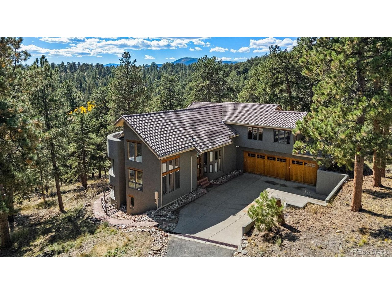 Welcome to your ultimate modern and private mountain retreat in the foothills of Golden. This spectacular home was recently renovated down to the studs, seamlessly blending exquisite architectural details with modern luxury on a private 4-acre lot just 15 minutes from downtown Evergreen and Golden. The main level boasts soaring ceilings, exposed beams, ornate wood trim, and solid wood doors. A spacious great room features a rounded sitting alcove, a dramatic three-sided fireplace, and massive picture windows framing serene nature views. French doors lead to one of three total decks nestled among the trees. The chef's dream kitchen includes a large island, premuim appliances, stone counters, and a large walk-in pantry.  A convenient mudroom with a custom live-edge bench is right off the garage. For remote work, the grand, high-ceiling office serves as a true showstopper, complete with a floor-to-ceiling rustic bookshelf and a unique timber loft. The primary suite is a private oasis, offering its own attached deck, a large walk-in closet, and a spa-like bathroom with a dual vanity, soaking tub, and a large walk-in shower with a rainfall fixture. Nearby, a flexible second upstairs bedroom/office holds excellent potential for a future en-suite conversion. The bright, walk-out lower level feels like main-floor living, showcasing a wall of windows across two spacious bedrooms-both featuring dedicated en-suite bathrooms. Enjoy complete peace of mind with a newer, hardwired Generac generator system, and newer boiler and electrical. Located just down the street from the 2,400-acre Genesee Mountain Park and the Beaver Brook Trail system, this property delivers the perfect balance of secluded mountain peace and easy access to I-70, El Rancho/Bergen Park.