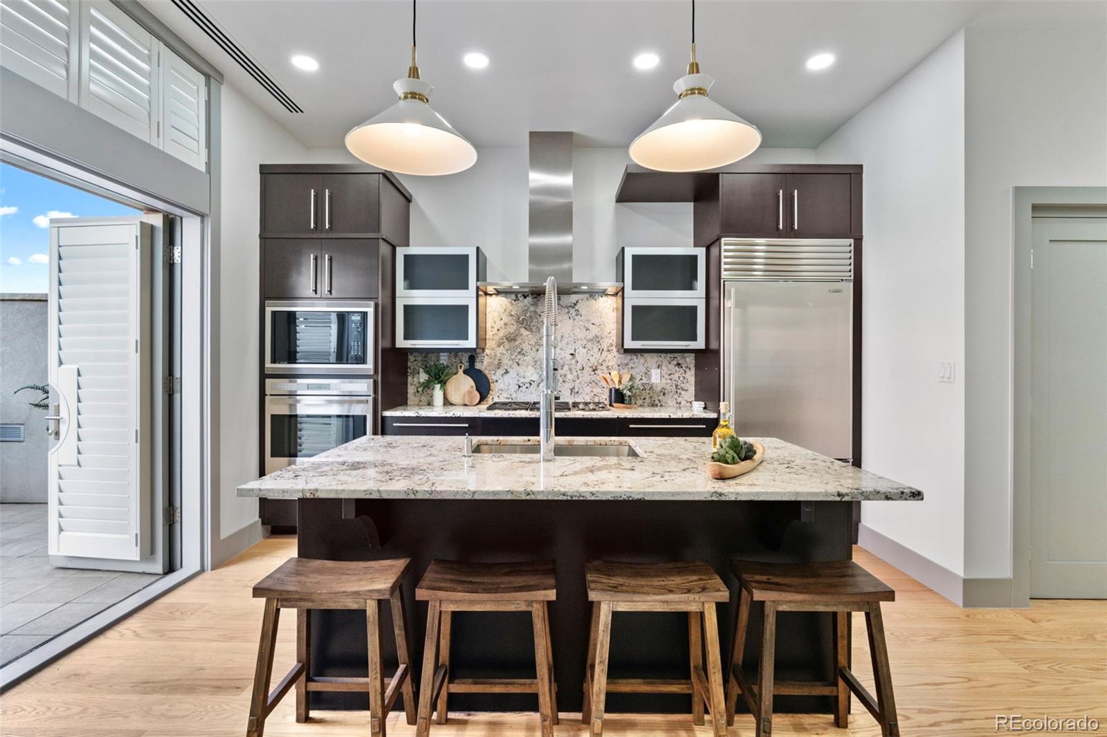 Nestled in the heart of Cherry Creek North, this sophisticated brownstone-style residence at NorthCreek offers an elevated lock-and-leave lifestyle in one of Denver’s most coveted communities. One of only a limited number of townhome-style residences within the building, Unit #204 combines the privacy and comfort of a single-family home with the convenience of luxury condo living. Thoughtfully designed with an interior elevator servicing all levels, the home delivers effortless accessibility without compromising style or function.Inside, soaring ceilings, expansive windows, rich hardwood flooring, and a gas fireplace create a warm yet refined atmosphere filled with natural light. The open-concept main living area flows seamlessly into a beautifully appointed kitchen featuring premium stainless steel appliances, slab granite countertops, custom cabinetry, and an oversized island ideal for entertaining. The spacious primary suite offers a serene retreat complete with a spa-inspired bath and generous walk-in closet, while the secondary bedroom includes its own ensuite bath with upscale finishes.Enjoy Colorado’s sunshine from the private outdoor terrace, perfect for morning coffee or evening dining. Additional highlights include designer lighting, custom details throughout, and two reserved parking spaces in the secure heated garage with EV charging capability. Offering 24/7 concierge service along with a secure gated entrance, providing unmatched convenience and peace of mind. Just steps from world-class dining, boutique shopping, galleries, and everything Cherry Creek North has to offer, this residence embodies luxury, comfort, and effortless urban living.