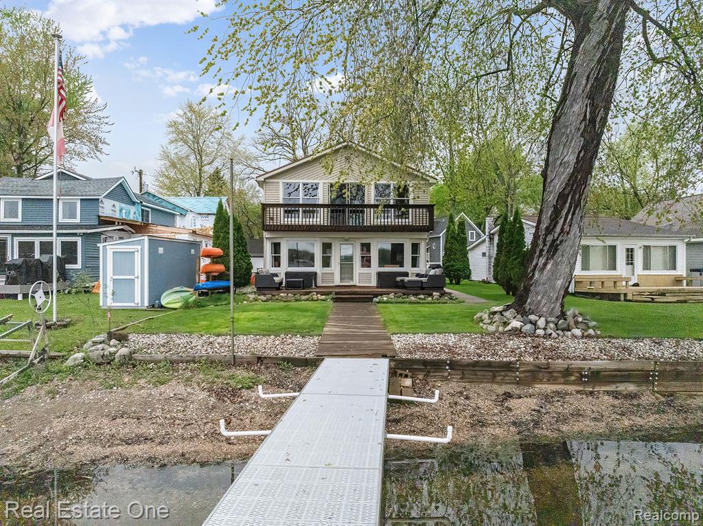 Welcome to the Chain of Lakes! This home sits on 47 feet of direct shoreline with a sandy beach, private dock, and wonderful sunrise views on Strawberry Lake. Step inside and you’ll immediately feel the charm, where natural materials and lakeside vistas create a true escape. The dining room features rich wood floors, cabin-style ceilings, and a skylight that fills the space with light. It flows easily into the kitchen, featuring warm wood cabinetry, stainless steel appliances, and a durable ceramic tile floor. A peninsula counter invites guests to gather, whether you’re hosting lively lake days or sharing a quiet meal at home. The living room captures the essence of cozy lake living with wood-paneled walls and a wood-burning stove. Just beyond, the family room and breakfast nook frame the water through a wide bay window - bringing every sunrise and sunset right into your home. Upstairs, the primary suite offers the ultimate retreat with a walk-in closet, private bath, and an expansive balcony overlooking the lake. Three additional bedrooms and a full bath provide plenty of space for family and guests. A detached three-car garage ensures room for all your lake toys and gear, while the outdoor spaces make summer living effortless: boating, swimming, bonfires, and endless sunsets are right outside your door. This is more than a home—it’s a lifestyle on the Chain of Lakes!