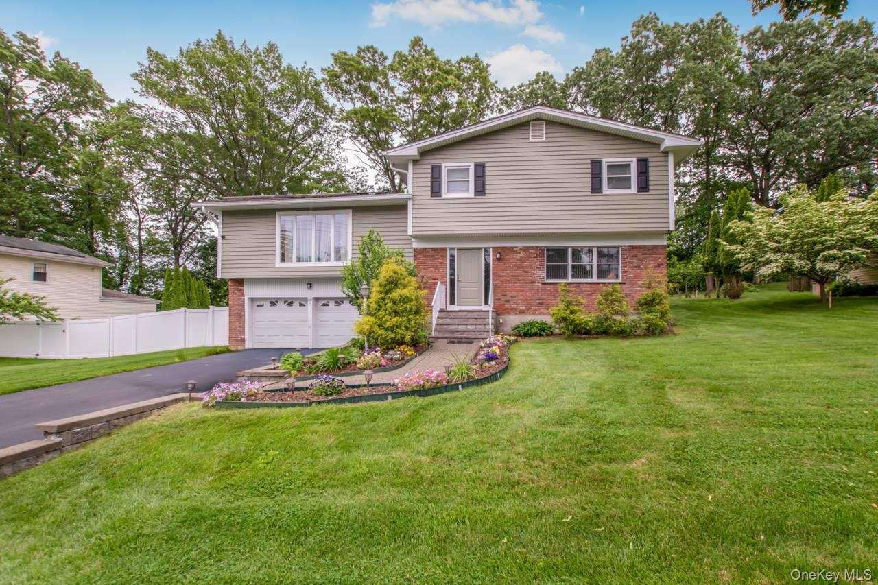 Meticulously maintained split-level home in Elmsford with major upgrades completed within the past 5 years, including a new roof and skylights, siding, windows, central AC, heating system, sprinkler system, fencing, and a brand-new front door. The main level boasts a spacious living room with vaulted, beamed ceilings. The updated kitchen features granite countertops, a center island, stainless steel Samsung appliances, and opens to a formal dining room with skylights, a crystal chandelier, and access to a rear deck with a outdoor hot tub—perfect for entertaining. The second level offers three large bedrooms and two fully remodeled bathrooms, including a master bath with double vanity. The lower level includes a large entertainment room with a fireplace and half bath. Additional flex space under the deck and a huge private backyard backing up to a golf course complete the package. Prime location near Rumbrook Park, Metro North stations, and major highways for easy NYC commuting.