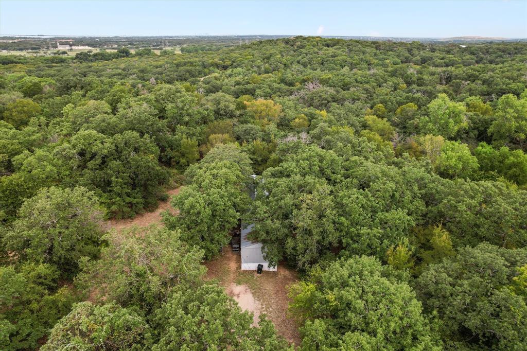2.4 Wooded Acres with Endless Possibilities – Outside City Limits!  Escape the hustle and bustle and embrace the tranquility of nearly 2.4 wooded acres just outside the city limits with no known restrictions! Whether you're dreaming of building your forever home or seeking a peaceful retreat, this property offers the flexibility and freedom to bring your vision to life.  Currently a habitable mobile home sits on the property, perfect for living in while you build your dream home.  The existing driveway partially crosses a neighbor’s land, but there’s ample road frontage to construct your own private entrance.  Enjoy the convenience of a private well (pump replaced in 2021) or connect to Bethesda Water, which recently extended service to the area and installed a meter box at the street.  The well covered by a canopy is located on the left side of the property.  Internet Ready with Spectrum and AT&T Fiber already available to the area for high-speed internet access.  Remnants of a previous structure (concrete stoop and black pipe) suggest a possible old septic system is located in a grove of trees near the middle front of the property.  There is partial wire fencing along the north boundary.  This land is a rare find — offering privacy, potential, and proximity to modern utilities. Whether you're looking to build, invest, or simply enjoy the space, this property is ready for your next chapter.