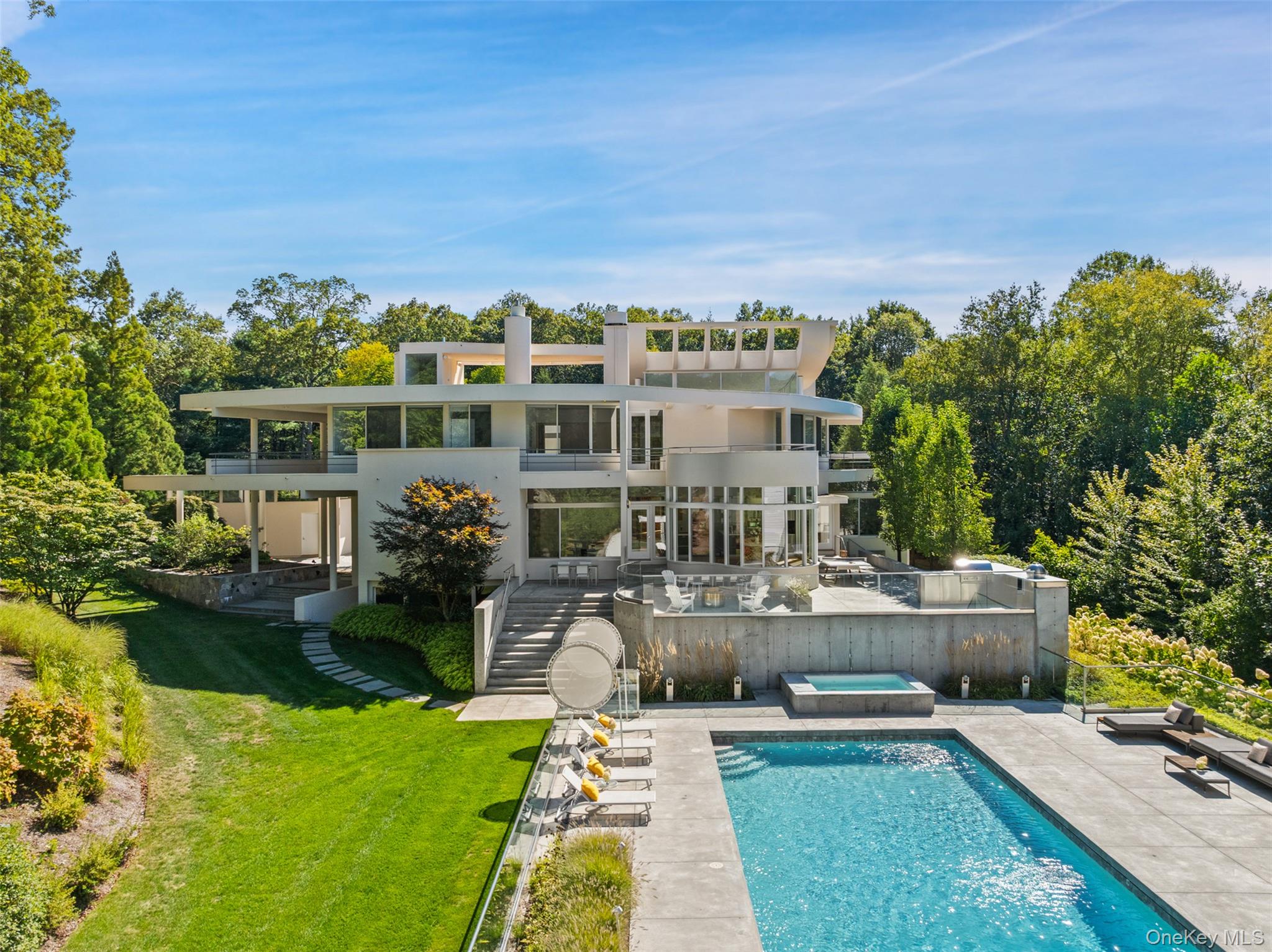 A MODERN MASTERPIECE - Impressive and dramatic with soaring ceilings, phenomenal light and artistic angles. Impeccably appointed 10,000 square feet with beautifully proportioned rooms—perfect for entertaining on the grand scale. Incredible Atrium Entry. Stunning Living Room with herringbone oak floor, massive stone-faced fireplace and tiger maple built-in with wet bar. Library with Fireplace. Dining Room with dramatic curved wall. Poggenpohl gourmet  Kitchen with Sitting Area with fireplace. Private Primary and Guest Suites. Four additional Bedroom Suites. Playroom. Billiard Room. Nearly twelve acres, on two parcels, in one of Pound Ridge's established estate areas. Incredible landscaping with dramatic rock outcroppings and exquisite plantings--majestic Oak, Kousa Dogwoods, Weeping Cherry, Sugar Maple, Plum, Blue Cedar, Crabapple, Burning Bush and Viburnum. Wrap-around terraces and decks overlook the Pool and Tennis Court. Spectacular architect-designed Pool House for the ultimate entertaining experience.