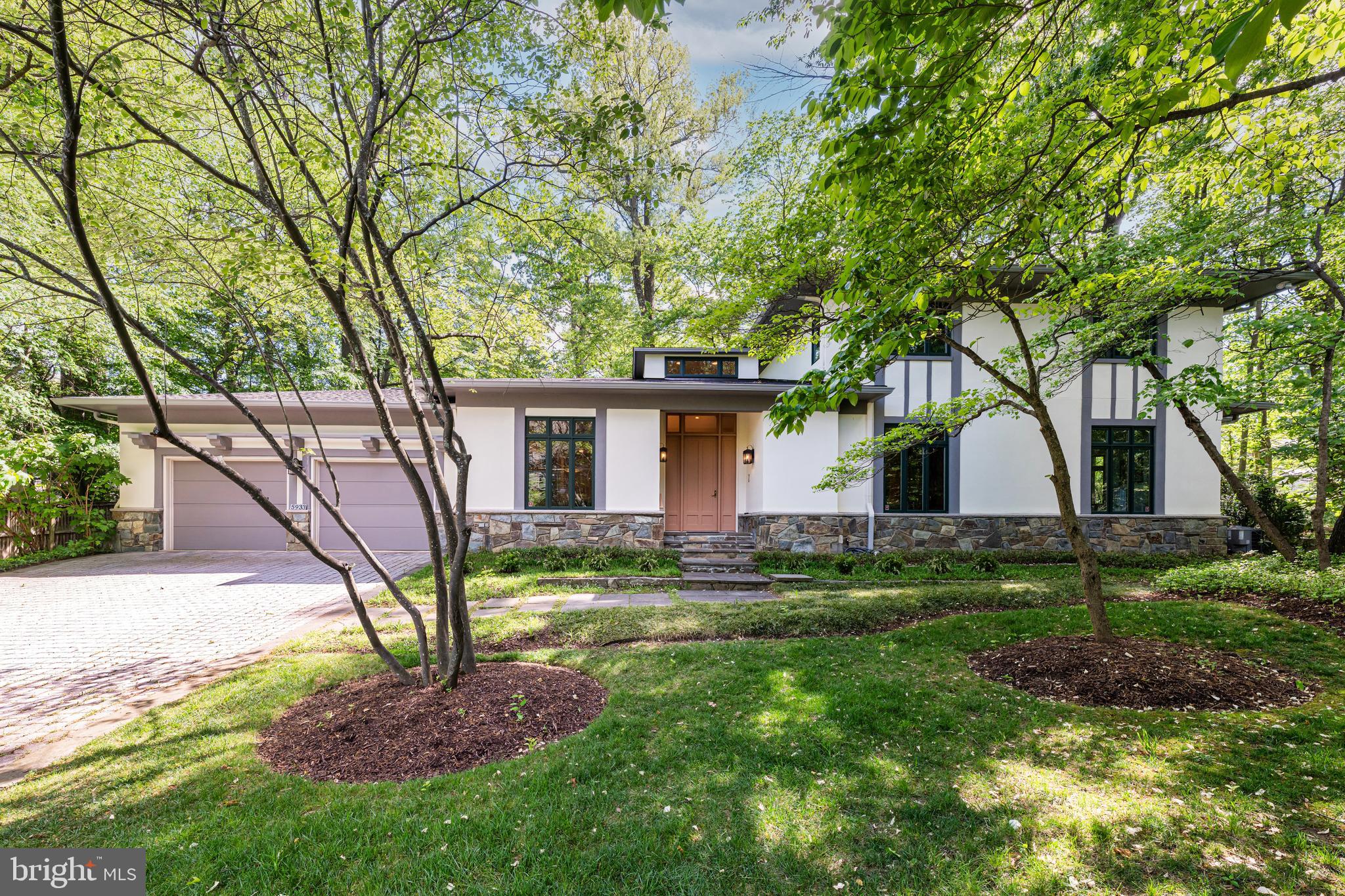Located in Chesterbrook Woods—one of McLean’s most sought-after neighborhoods—5933 Woodley Road offers true main-level living with generous space to grow, entertain, and enjoy everyday life, all just one stoplight to Washington, DC. Custom built in 1998, this 5 Bedroom, 3.5 Bathroom home sited on a .47-acre lot thoughtfully expresses a mid-century modern design with clean lines, integrated built-ins, expansive windows, and soaring ceilings, creating a light-filled, open atmosphere that feels both sophisticated and warm. The main level is tailored for effortless living, featuring a spacious primary suite, mudroom with laundry, and direct access to the two-car garage—all on one floor. Enter through a dramatic two-story foyer into beautifully proportioned living spaces, including a sunlit great room with 10’-foot tray ceiling, custom cabinetry and a gas fireplace, a formal dining room with built-ins, and a private office with double doors. The kitchen is well-appointed with granite countertops, quality appliances, and a seamless connection to the breakfast area and outdoor spaces, perfect for everyday living and entertaining. The primary suite is a quiet retreat, complete with an adjacent sitting room accessed via pocket doors - ideal for a private office, nursery, den, or additional bedroom. The en-suite bath offers dual vanities, a jetted soaking tub, walk-in shower with bench, and a separate water closet, along with abundant natural light. A well-appointed powder room is also conveniently located on the main level. Upstairs, three generously sized secondary bedrooms, one with en-suite bath and the other two with access to a full hall bathroom, provide flexibility for family and guests, while the expansive unfinished lower level offers incredible potential—whether you envision additional living space, a home gym, theater, or all of the above. Recent updates, including a new roof, refinished hardwood floors, new carpet, and refreshed interiors enhance both comfort and peace of mind, while the home’s thoughtful layout and quality construction provide a rare opportunity to move in and make it your own.  Surrounded by mature trees and set on a picturesque .47-acre lot, this property offers a rare blend of location, design, ease, and livability with a tranquil setting and easy access to parks, top-rated McLean schools, shopping, and major commuter routes.