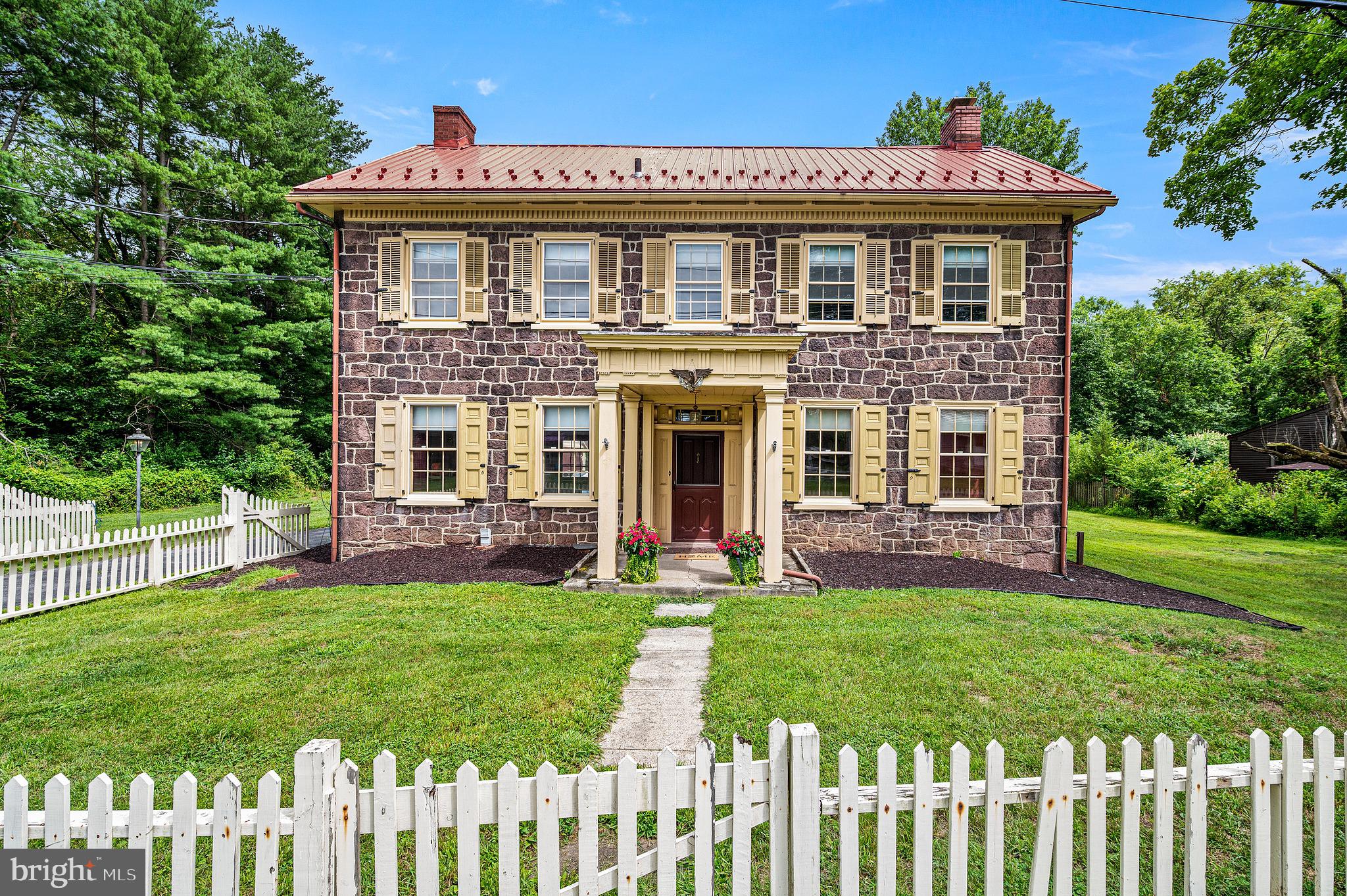 Step back in time without giving up today's comforts in this extraordinary circa 1825 brown sandstone home, where nearly two centuries of craftsmanship have been lovingly preserved. Constructed of solid brown sandstone and rich with authentic architectural details, this 5 bay center hall federal style home tells a story in every room. The original owner served as the bookkeeper at nearby Hopewell Furnace, and over the years the property has worn many hats - including its days as the well-known commercial poultry operation, Hainey’s Hen House. From the moment you arrive, you'll appreciate the timeless character that simply can't be recreated.Inside, you'll find six original decorative fireplaces, beautiful real wood floors, deep window sills, original built-in cupboards, and historic millwork that has gracefully stood the test of time. The spacious center hall welcomes you inside and opens to a light-filled living room, while the elegant dining room showcases an original mantel, charming built-ins, and connects to the rear hall with its original back staircase. A convenient first-floor powder room adds a welcome touch of modern functionality without compromising the home's historic charm.The spacious, primitive-style kitchen offers a simple, functional layout that leaves plenty of opportunity for your own vision and updates. Twin built-in cupboards flank the original fireplace, complete with its historic cooking crane - a wonderful reminder of the home's early days. Just beyond, the original combination summer kitchen / smokehouse remain, adding yet another layer of character and history that is rarely found today. Upstairs, four generously sized bedrooms continue the home's rich character, with three featuring their own fireplaces and built-ins. A central full bath and a cozy sitting room or home office with access to the rear staircase complete the second floor. A walk-up attic provides copious amounts of storage space. History meets modern convenience with the addition of central air conditioning, while outside an oversized detached two-car garage provides plenty of space for vehicles, hobbies, or storage. In the backyard, the picturesque remains of an old stone barn offer endless possibilities-whether preserved as a stunning historic feature, transformed into a garden focal point, or thoughtfully repurposed into something truly special.Some homes are simply places to live. Others become part of your story. Rich in history, overflowing with character, and impossible to duplicate, this remarkable property is ready for its next steward. Come experience the warmth, craftsmanship, and timeless beauty that have made this home so special for over 200 years.
