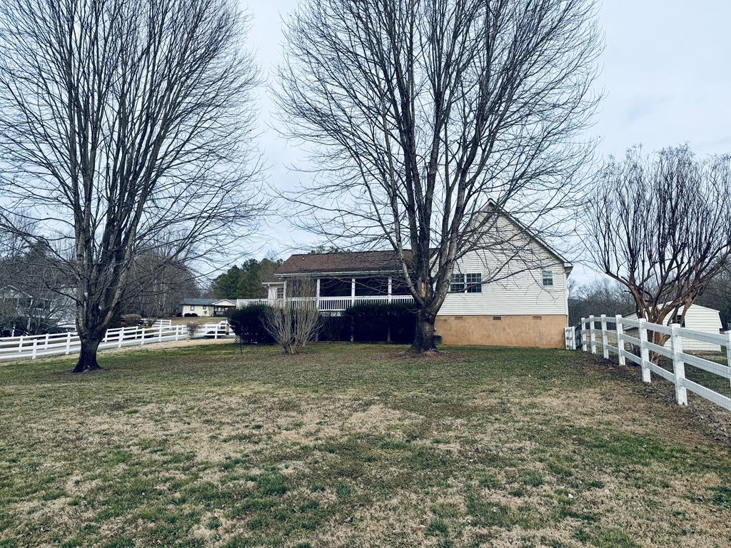 This exceptional three-bedroom, three-bathroom traditional home in Hayesville, North Carolina, features a formal entry leading into a well-designed layout with a dedicated office and functional laundry room. The central living room offers a gas fireplace with a mantel and accent lighting.  The main bedroom serves as a private retreat with direct access to a screened porch and an en suite bathroom featuring a double vanity, linen closet, walk-in shower, and soaking tub. A split floor plan provides a second bedroom and bathroom on the opposite side of the home, while the upper level includes a guest suite complete with a walk-in closet.  The eat-in kitchen features solid countertops and opens directly to the screened porch and a deck ideal for grilling. The outdoor space is a highlight of the property, offering a fully fenced backyard that extends to a serene creek. Additional amenities include a two-car garage, storage building, and easy access to local groceries and Lake Chatuge.