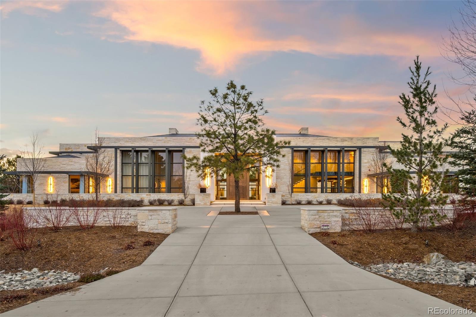 Located in Cherry Hills Village just one mile from Cherry Hills Country Club, this newly completed modern estate sits on 2.5 private acres inside a 24-hour gated and manned community and offers over 13,000 finished square feet of indoor-outdoor living.A 16-foot custom Italian steel entry door opens to soaring 20-foot ceilings, expansive glass, and towering sliding doors that create seamless access to a resort-style travertine pool deck, knife-edge pool and spa, and a fully equipped pool house surrounded by manicured lawn and landscape. Designed for buyers searching for indoor-outdoor living, privacy, and entertaining space, this home delivers a true retreat setting.The main-level primary suite is privately positioned in its own wing and includes a sitting room with fireplace, dual walk-in closets, and a spa-inspired bath with dry sauna and steam shower. A private staircase leads to a secluded second-story office with mountain views and adjacent unfinished space ideal for a boutique closet or additional wellness room. A light-filled exercise studio completes the primary wing.The modern chef’s kitchen features Gaggenau, Wolf, and Dacor appliances plus a full dirty kitchen/prep kitchen designed for effortless entertaining. A main-floor office and a private guest suite with five-piece bath and zero-entry shower offer one-level living for guests.A showpiece 8-car garage with EV chargers includes a full glass wall overlooking the pool deck — a rare feature for collectors and car enthusiasts.Upstairs, accessible by a floating staircase or a private elevator, are three spacious ensuite bedrooms.The lower level includes a theatre room designed for an immersive movie experience.Outdoors, multiple dining, sitting, and soaking areas surround the pool and spa, while the pool house offers a bar and prep space — ideal for buyers searching for a resort-style backyard, outdoor entertaining, and luxury privacy in Cherry Hills Village