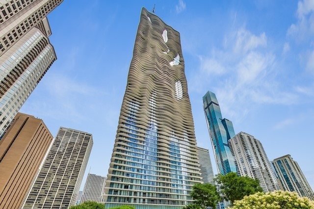 Experience views of the lake and city from this top floor - penthouse unit in Chicago's Aqua Tower. Award-winning architect Jeanne Gang designed this building's unique, slow rippling balconies, giving the skyscraper a sculptural quality. This residence offers a terrace that spans 91 feet in length with access from the living spaces and all four bedrooms. Recently updated with new weather-proofed flooring, this serene outdoor space is perfect for entertaining, relaxation, and meditation. Abundant natural light flows from floor-to-ceiling windows in every room. 14 ft ceilings and vast wall space create the ideal space to display an art collection. Highlights include Lutron motorized shades, crown molding, millwork, and hardwood floors throughout the home. The living space flows together flawlessly: a living room with fireplace, a dining area large enough to accommodate both large parties as well as intimate gatherings. Tastefully appointed, the kitchen offers Calacatta Gold marble counters, custom cabinetry, Subzero, Wolf, and Miele appliances, and an island with breakfast bar. The current owner created an elegant, temperature-controlled wine cellar in an area once dedicated to storage. A dramatic, newly renovated powder room features new wood paneled walls and a floating sink atop lit Onyx counter. The graciously sized primary suite features a grand walk-in closet outfitted by Closet Works and a luxurious ensuite bath with custom cabinetry in a cocoa finish, Calacatta Gold countertops, mosaic marble shower, and Airbath Jacuzzi tub. The spacious second and third bedrooms have generous closets and stunning views; two full baths are located across the hall. The fourth bedroom is currently configured as a den with custom built-ins. One deeded parking space included in the price and a second deeded space potentially available at an additional cost. Residents enjoy Aqua's full amenities: indoor and outdoor swimming pools, hot tub, sundeck, fitness center, sauna, steam, indoor basketball court, outdoor running track, media/theatre room, billiards room, business center, restaurants and direct access to the city via the Chicago pedway.