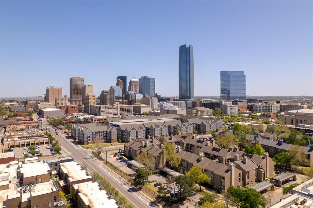 Seeking location, value and a lock-and-leave lifestyle? Sycamore Square delivers. This established gated condo community in downtown Oklahoma City offers an approachable entry into city living, placing you in the middle of everything that makes downtown such a vibrant place to live. Positioned on the third level, this corner unit benefits from added privacy and a quiet, comfortable feel within the community. Inside, the condo blends character with practical updates, beginning with a thoughtfully designed kitchen featuring stainless steel countertops, a white subway tile backsplash laid in a herringbone pattern and an additional granite counter with bar seating well suited for everyday meals, morning coffee or casual entertaining. The living area is warm and functional with a stacked stone fireplace and engineered wood flooring, creating an easy space to relax or gather. The primary bedroom enjoys ample natural light and includes an ensuite bath with a tile shower, heated tile flooring and modern finishes with generous storage. An adjoining room connects directly to the primary bedroom, offering additional space for a study or private retreat. The secondary bedroom includes its own ensuite bath, making it well suited for guests or everyday living. Community amenities include a pool and hot tub located on the property and covered, dedicated parking adds everyday convenience. With quick access to the Arts District, Midtown, Scissortail Park, the Paycom Center and nearby local restaurants, this downtown Oklahoma City condo stands out as a practical downtown residence. It offers incredible value, livability and long-term potential.