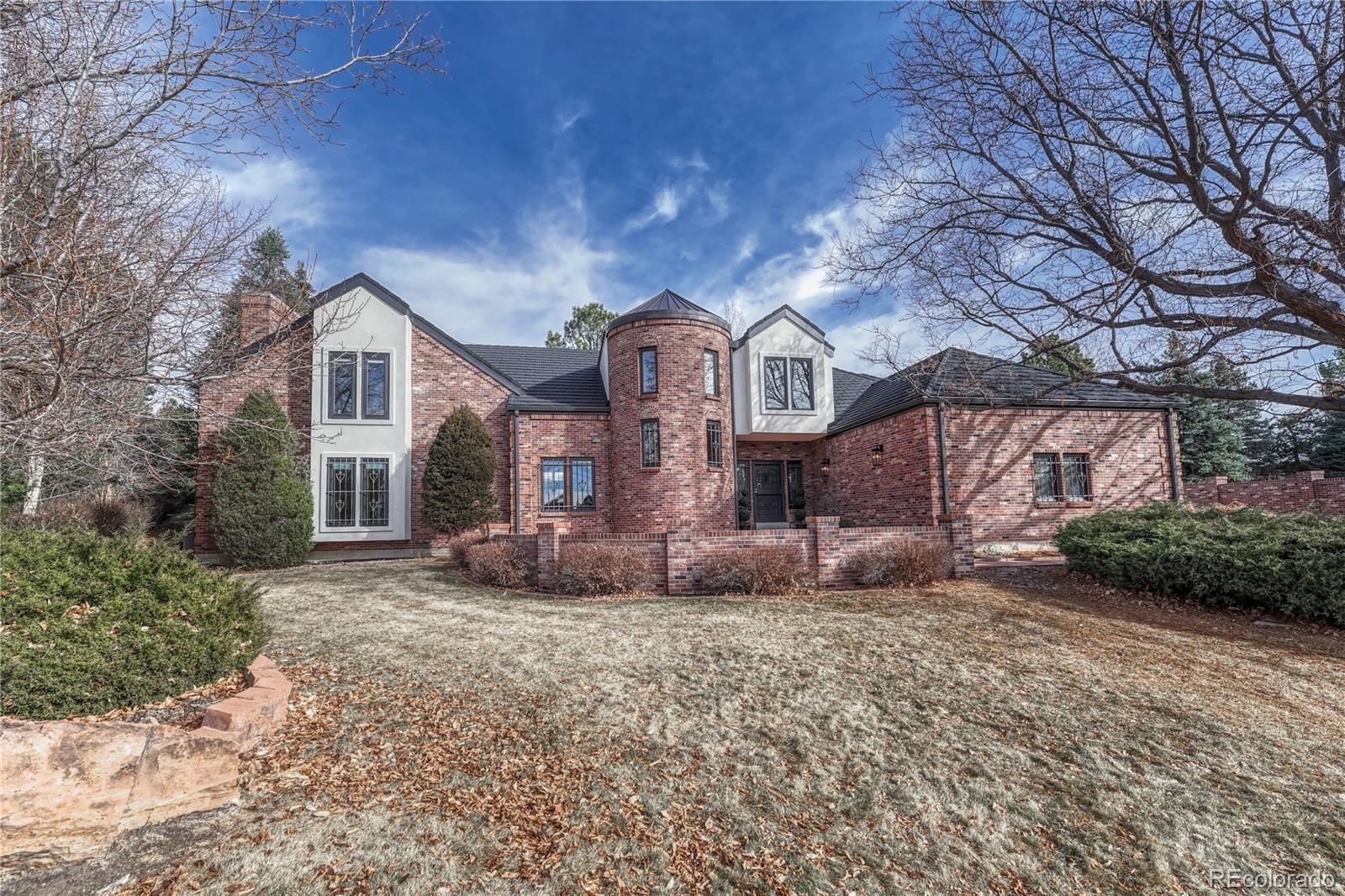 TIMELESS TUDOR tucked at the end of a quiet cul-de-sac on just under an acre in highly desirable Greenwood Village. Enjoy mountain views on nearly 9,500 square feet of classic architecture offering scale and exceptional entertaining potential. Six generously sized bedrooms, all with ensuite baths and a split floor plan providing separation throughout. Primary suite options on both the main and upper levels offer flexibility ideal for multigenerational living. Rich wood beam ceilings, traditional wood detailing, and a striking copper turret highlight the enduring craftsmanship rarely found today. ENTERTAINING SPACES: Designed for gathering indoors and out with multiple living areas, front courtyard, and an oversized back paver patio ready for hosting and events. All surrounded by mature landscaping, gardens and water features. KITCHEN: Custom brick hood over the cooktop, center island, and eat-in area with direct access to the formal dining room. MAIN FLOOR: Spacious family room with wet bar, two half baths, primary and secondary bedroom suites and seamless flow to outdoor spaces. UPSTAIRS: Light filled loft retreat ideal for relaxing or unwinding. Private primary suite with French doors, fireplace, walk-in closets, and ensuite bath with an additional fireplace. Also, a secondary ensuite flexible as a bedroom or office with adjacent conference style space or closet, steam shower, and sauna. FINISHED BASEMENT: Two additional bedroom ensuites, large family room with wet bar, wine cellar, and a bonus room ideal for fitness, media, or hobby use. HOME EXTRAS: Recent $200k exterior improvements including a 50-year stone coated steel roof, new gutters, stucco replacement, and exterior paint. New dishwasher. 3 car garage with 220 outlet. Dual zoned HVAC. Seven fireplaces. Extensive storage. No HOA. West facing front yard allows for easy snowmelt. Architectural presence and scale invite thoughtful updates for a discerning buyer who values space, privacy, and timeless design.