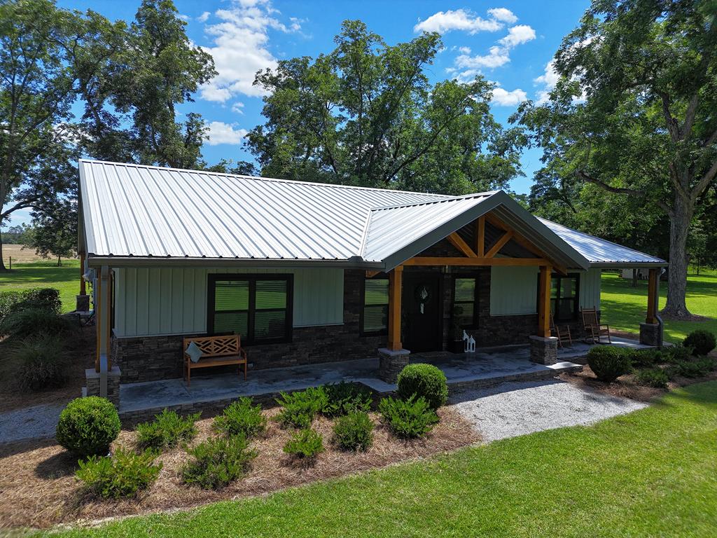 You have to see this EXTRAORDINARY CUSTOM BARNDOMINIUM in Whigham, GA! Amazing details, beautiful open living space with Juniper ceiling and walls and farmhouse finishes make this the PERFECT family homestead. The living room features soaring ceilings, a great stone fireplace, hanging barn doors and warm country accents. The kitchen is immaculate with custom countertops, a center island with farm sink, Cafe' appliances and a wonderful pantry with screen door. The primary suite is HUGE with lots of bright windows, and a luxury bathroom with custom cabinets and drawer, unique shower, and access to the equally beautiful laundry room. At the other end of the house, two cute bedrooms share another well appointed bathroom. Outside, you will find the perfect outdoor space for entertaining under the huge covered patio, complete with bar, kitchen and grilling station, and plenty of room for tables and outdoor furniture. Other details include extra insulation, large attic space, tankless water heater a Generac generator  MORE. All this on a .69 acre-property with wired workshop/utility barn. Call your favorite agent TODAY for a closer look at this extraordinary home!! Click here for virtual tour: https://my.matterport.com/show/?m=9EPn7Tn9PLX&mls=1