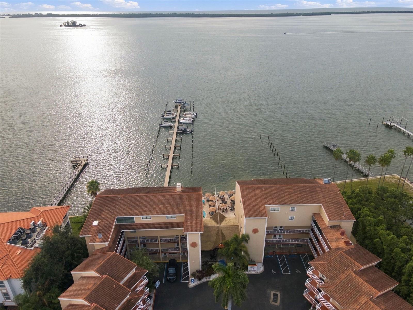 Where Every Day Feels Like Vacation! Short-term rentals permitted. Own a piece of the waterfront at Beso Del Sol, a coastal community offering investment potential, vacation rental appeal, and access to the beautiful waters of St. Joseph Sound. This fully furnished 4th-floor studio offers an opportunity to generate rental income while enjoying the property for your own Gulf Coast getaways. The open layout features tile flooring, solid-wood cabinetry, an efficient kitchen with an eat-in area, and a comfortable living and sleeping space with a king bed. Updated furnishings include a 60 inch smart TV, loveseat, dining table and chairs, and outdoor bistro table and chairs, giving the property a refreshed, inviting feel and making it ready for personal enjoyment or rental use. Step onto the covered deck for additional outdoor living space and a place to enjoy the surroundings. Beso Del Sol offers a waterfront setting with an adult-only heated pool, a second heated pool, spa, waterfront dock, fishing, and Marker 8 Tiki Bar & Grill right on the property. Relax poolside, enjoy a drink by the water, fish from the dock, or take in beautiful sunsets. On-site rental management is available. Conveniently located near downtown Dunedin, the Pinellas Trail, Dunedin Marina, Honeymoon Island, Caladesi Island, and the Gulf beaches, with dining, shopping, boating, fishing, and outdoor recreation all nearby. This furnished unit combines income potential, resort amenities, and a prime coastal location.