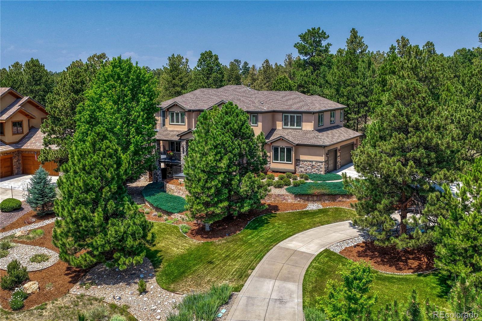 Thoughtfully updated and meticulously maintained, this exceptional Timbers residence sits on a cul-de-sac street and backs to open space, offering a rare combination of privacy, tranquility, & mountain views. Perfectly positioned on the lot, the home was designed to maximize both its surroundings and stunning views of Pikes Peak. Enjoy peaceful mornings from the covered front porch. The heart of the home is a fully remodeled kitchen featuring custom cabinetry, premium stainless-steel appliances, a Sub-Zero refrigerator, walk-in pantry, & a butler's pantry. Beautiful solid oak flooring. The family room is anchored by a stately fireplace & a dramatic 2-story wall of windows that fills the space with natural light while showcasing views of the backyard water feature, fire pit, and open space beyond. The main level also includes a guest bedroom with an ensuite bath, private office, formal dining room, breakfast nook, and dedicated laundry room with built-in cabinetry and utility sink. Upstairs, the primary suite offers a private balcony, spacious walk-in closet, and luxurious five-piece bath, and an adjacent room that could be used as a private sitting room, nursery, or exercise space. A rare bonus room with a three-quarter bath and private exterior entrance provides endless flexibility as a fitness studio, home office, media room, guest retreat, or playroom. Each secondary bedroom features its own ensuite bath, offering comfort and privacy for family and guests. The walkout basement is built for entertaining, with a wet bar, beverage cooler, fireplace, billiards area, ping-pong space, and TV lounge for game days and movie nights. There are two additional bedrooms with a Jack and Jill bath in the basement. Outdoor living is equally impressive, with multiple spaces for relaxing and entertaining. The covered front porch captures beautiful mountain views, while the backyard patio, built-in fire pit, and soothing water feature create a private outdoor retreat.