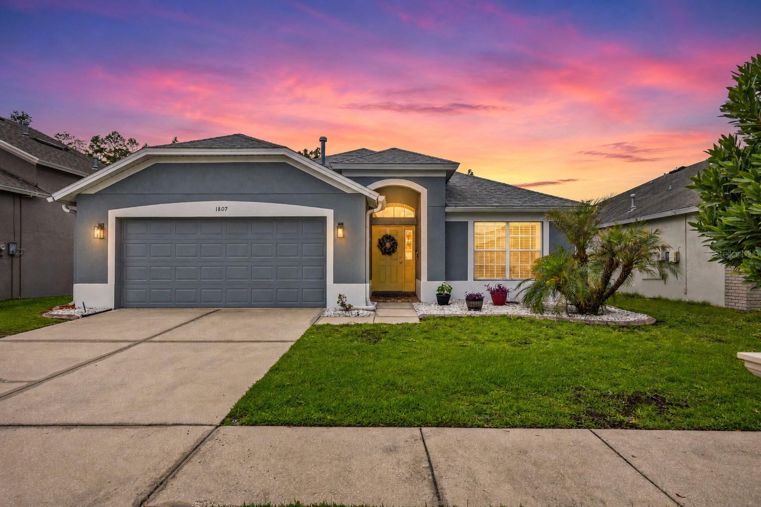 Resting on a picture perfect lot with welcoming curb appeal and nothing but trees as your rear neighbor, this 4 bedroom, 2 bath pool home is tucked within the gated Heatherstone neighborhood of Meadow Pointe III! A 2021 roof, 2022 AC, and a central Wesley Chapel location add even more value to this inviting home. Inside, wood flooring runs through the formal dining room, light and bright living room, and privately split primary bedroom. High ceilings give the main living area an open feel, while sliding glass doors draw your eye straight out to the pool deck. Overlooking it all, the eat-in kitchen is nicely appointed with stainless steel appliances, a natural gas range, stainless steel apron sink, granite countertops, generous pantry storage, and dinette seating. Just off the kitchen, the laundry room and access to the oversized garage are conveniently placed for easy unloading and everyday chores. Privately set apart from the secondary bedrooms, the owner’s suite enjoys serene backyard and pool views, along with a spacious ensuite featuring a jetted tub, walk-in shower, dual sinks, and a large walk-in closet. Across the home, bedrooms 2 and 3 offer plush carpet flooring, ceiling fans, and convenient access to the second full bathroom. Near the front of the home, bedroom 4 adds an interesting layer of flexibility. With double-door entry and its current setup as an extra living room, it could easily serve as an office, playroom, media space, or true fourth bedroom. Made for entertaining and everyday family life, the layout offers the perfect balance of openness and privacy before extending outdoors to an impressive poolside retreat. A paver pool deck and lanai provide plenty of room to relax, with a covered seating area for shade and a sparkling swimming pool with solar heat added in 2021. With trees beyond the backyard and no rear neighbors, the setting feels peaceful, private, and easy to enjoy. The gated Heatherstone at Meadow Pointe III offers access to community amenities including a swimming pool, clubhouse with fitness center, sports courts, playground, and more. Close to major highways and all of Wesley Chapel’s shopping, dining, and entertainment, this home is ready to welcome its next owner. Call today to schedule your private showing!