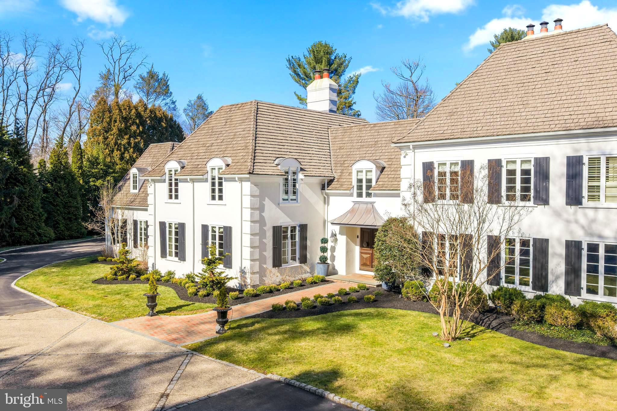 Set along the tree lined stretch of Parkes Run Lane in Villanova’s Radnor Township, this stunning French Colonial inspired home sits on more than an acre of level ground behind a private gated entrance. From the moment you step into the foyer, a dramatic front to back view draws your eye straight through to the pool and peaceful backyard, setting the tone for the home’s elegant design. The main level features beautifully proportioned living spaces including a welcoming living room, sophisticated den, and formal dining room. Custom doors, expansive rooms, and graceful archways throughout the home create a seamless sense of flow and style. The impressive gourmet kitchen serves as the centerpiece of the home, complete with a large island with seating, walk-in pantry, second sink, built-in desk area, and a bright breakfast room overlooking the pool and backyard. Entertaining is effortless, with the dining room connected to the kitchen through a fully equipped butler’s pantry offering an additional sink, oven, beverage refrigerator, and ice maker. The dining room also features an artist painted wine closet. Just off the kitchen is a spacious step down family room with abundant built-ins and plenty of room for gathering and relaxing. A generously sized mudroom with a sink and cubbies for eight or more helps keep daily life organized.The expansive lower level includes the inviting “Pub Room,” highlighted by classic Chicago brick flooring and direct access to the private backyard and pool area. This level also features a full bathroom with steam shower, ample storage closets with one containing a washer and dryer. Upstairs, the luxurious primary suite provides a peaceful retreat with a sitting area, dressing area, an abundance of closets, and a spacious bath. Six additional generously sized bedrooms, each with their own en suite bathroom and walk in closet, offer comfortable accommodations. One bedroom is privately positioned, making it ideal for guests, an au pair, or an in-law suite. A basement area with high ceilings includes a basketball hoop with room for practicing foul shots while another space is for gathering, exercising  and storage. Designed for easy indoor outdoor living, the home also offers a beautiful covered outdoor entertaining area just off the living room, complete with a fireplace and flat screen television. Located within the highly regarded Radnor School District and close to many top private schools, this home offers a wonderful lifestyle. Residents can enjoy easy access to the Radnor Trail, as well as nearby downtown Wayne with its shops, restaurants, train station, and the beautiful gardens of Chanticleer. Major commuting routes provide convenient travel to Center City Philadelphia and beyond.This exceptional Villanova property combines comfort and thoughtful design for entertaining in one of the area’s most desirable settings.