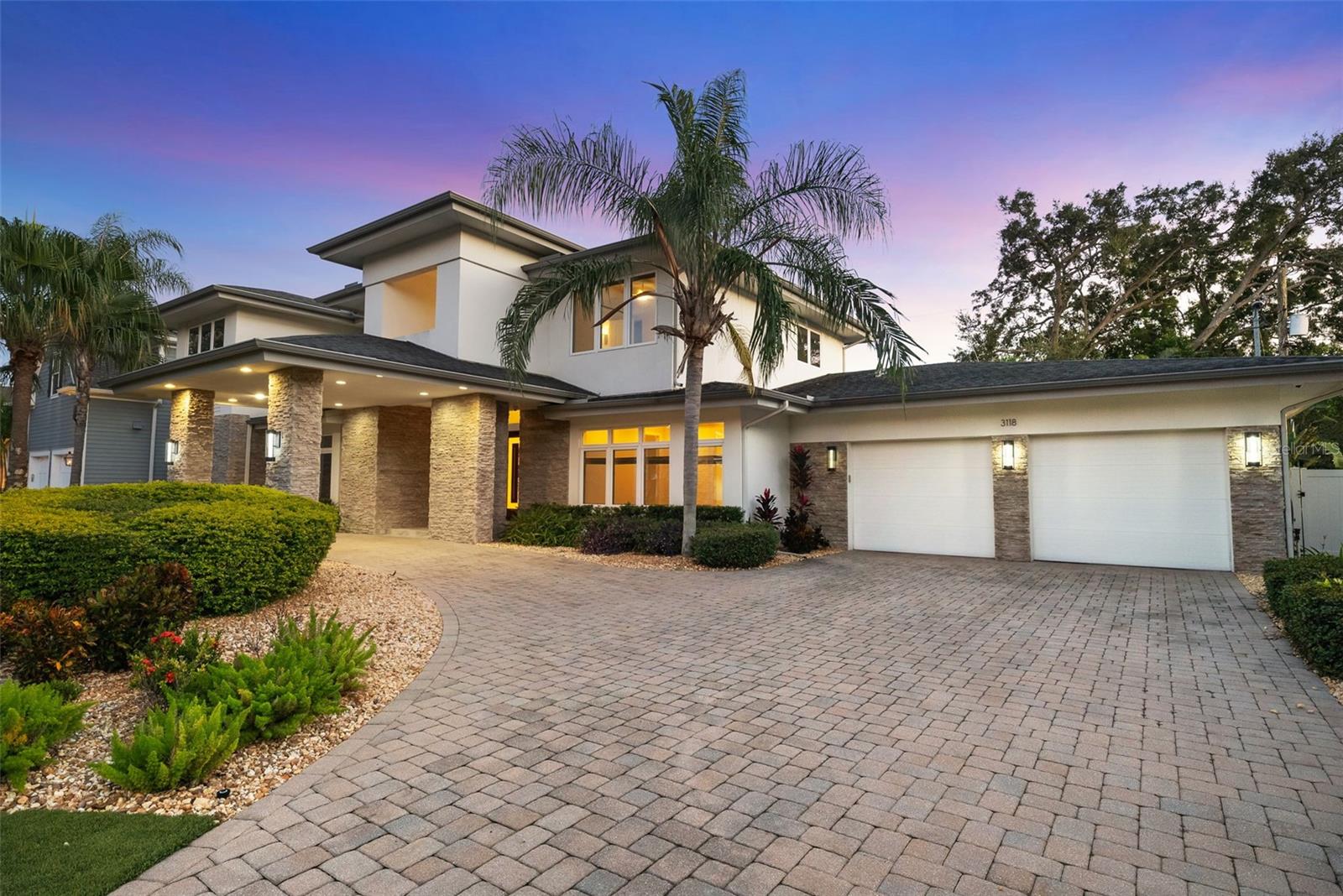 Flood Zone X and ideally located just off iconic Bayshore Boulevard and Tampa Bay, this meticulously maintained Taralon Homes custom residence offers over 4,700 square feet of thoughtfully designed living—an exceptional alternative to new construction in one of South Tampa’s most sought-after neighborhoods. Rare features include a 4-car garage, porte-cochère, and a first-floor primary suite, delivering both luxury and long-term practicality.A stately circular brick driveway and grand porte-cochère create a striking arrival, while the elevated homesite with manicured artificial turf and lush tropical landscaping provides timeless curb appeal with low-maintenance living. Inside, soaring ceilings, refined finishes, and elegant lighting create an atmosphere of understated sophistication.The chef’s kitchen is the heart of the home, showcasing sleek European-style cabinetry, quartz countertops, premium JennAir gas appliances, and three oversized islands ideal for cooking, serving, and gathering. Pocketed sliding doors seamlessly connect the expansive great room to a screened lanai designed for year-round enjoyment, featuring a fireplace, outdoor kitchen, and full privacy fencing. The heated plunge pool + spa (spool) offers a resort-caliber experience with a fraction of the upkeep, perfect for cooling off, hydrotherapy, and entertaining. A smart alternative for those who want the amenities and enjoyment of a pool experience with simplified maintenance.The first-floor primary suite includes a spa-style bath and custom closets, and is complemented by a private study and a flexible bonus room ideal for a gym, nursery, or second office. Upstairs, four additional bedrooms and a spacious entertainment loft provide generous accommodations for family and guests.Smart-home features include a whole-house Control4 system, security cameras, and a natural-gas generator for added peace of mind. Meticulously maintained and lightly lived in, this residence combines Flood Zone X confidence, immediate proximity to Bayshore Boulevard, and modern custom design—an increasingly rare opportunity in South Tampa.