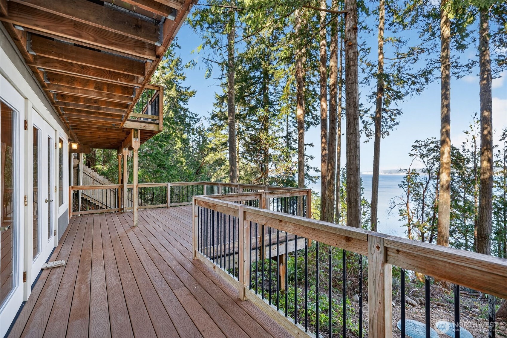 VIEWS and Waterfront Living! Vaulted ceilings and a dramatic wall of windows fill the living area with natural light and provide sweeping Sound views.  Living and dining areas flow seamlessly, anchored by two wood-burning fireplace inserts. (Good supply of firewood stays!) Multiple double doors extend the living space and give access to the full-length deck overlooking the water. Kitchen is both functional and beautiful, featuring abundant custom wood cabinetry offering ample storage and display workspace and water view. Adjacent dining area enjoys its own access to the deck, making indoor/outdoor dining easy. Primary suite is positioned to capture the view, with a slider to the deck overlooking the water, massive closets, and en-suite bath features heated floors, double vanity. True waterfront living is enhanced by a rare, grandfathered-in private dock that provides direct access and long-term value. BRAND NEW 4-Bedroom Septic System!