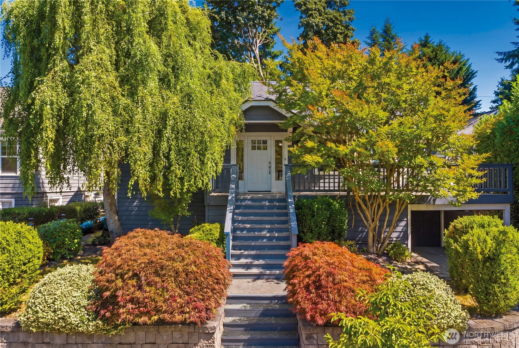A 1925 Magnolia Craftsman with the period character to prove it: cove ceilings, oak hardwood floors freshly refinished, and the millwork classic Seattle homes are known for. Magnolia Elementary is a three-minute walk, and Magnolia Village sits half a mile away. Inside, four bedrooms and three baths span 3,480 square feet. Enter off the large front deck to a spacious living room with a gas fireplace, a formal dining room, an updated kitchen, and two bedrooms with a full bath, plus a vaulted sunroom with French doors to the back deck and a sun-filled loft that doubles as a playroom or fitness space. The top floor is a private retreat all its own: a primary suite with ensuite bath, a separate office, and a private deck framing a view of Puget Sound. The lower level adds flexibility and potential rental income with a separate entrance, second kitchen, bedroom, full bath, laundry room, and attached one-car garage. Outdoors, the back deck and patio with a hot tub hookup opens to a private and serene 6,400-square-foot lot of raspberry bushes, blue hydrangeas, a dog run, and a full sprinkler system across lawn and beds. Beyond the front door, Magnolia Village delivers the best of the neighborhood: shops, bakeries, and a Saturday stroll to Petit Pierre, with Ella Bailey Park and its playgrounds close enough for a picnic. This is the type of home and neighborhood you plant your roots in.