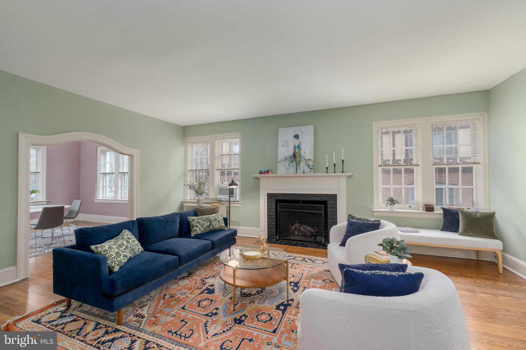 Tucked beneath one of Baltimore’s most beautiful mature tree canopies, Berkeley House stands with the quiet elegance of a 1920s architectural gem—stucco façade, classical detailing, and large multi-pane windows designed to fill each home with natural light. Set in the heart of Tuscany-Canterbury, Unit 2B is a rare residence where history, sunlight, and everyday ease come together just steps from Johns Hopkins, Wyman Park, and the best of north-Baltimore living.Inside, the scale and character of pre-war architecture immediately stand out: soaring ceilings, wide hallways with rich millwork, arched doorways, and the warm glow of 28 restored original windows. With south, east, and west exposures, the home is bright from morning to sunset, offering calming treetop and courtyard views throughout.The gracious living room features original hardwood floors, a working gas fireplace, and a sweeping arched opening into the formal dining room—an airy, window-lined space ideal for entertaining. A corner sunroom, surrounded on all sides by glass, makes a wonderful home office, creative studio, or potential third bedroom.The kitchen blends classic charm and functionality with checkerboard floors, white cabinetry, stainless steel appliances, and leafy views. Two large bedrooms anchor the private wing, each with its own full bath. The renovated ensuite bathroom is especially striking with deep navy tile, brass fixtures, and a boutique-inspired design.Thoughtful updates throughout respect the home’s architectural integrity: preserved hardware, plaster archways, period moldings, and soft, sophisticated color palettes.Berkeley House offers the feel of a private, residential enclave with only eight units, landscaped grounds, and a fenced backyard garden shared by the building. Unit 2B includes a private garage plus two additional outdoor parking spaces—a rare advantage in this highly walkable neighborhood.Unmatched location + lifestyle:• Johns Hopkins Homewood Campus – 2 blocks• Wyman Park – steps away for strolls, jogging, picnics, and wooded paths• Baltimore Museum of Art & Sculpture Garden – 5 minutes• Sherwood Gardens, Loyola, Union Memorial, The Rotunda – all nearbyNeighborhood cafés, culture & convenience:Enjoy coffee at Bird in Hand or On the Hill Café, brunch at Gertrude’s, evenings at Guilford Hall Brewery, and easy access to Charles Village shops, bookstores, and restaurants. Tuscany-Canterbury is known for its peaceful, tree-lined streets, historic architecture, and exceptional walkability.Berkeley House 2B is a home with character, light, and history—wrapped in the rare combination of green space, culture, and convenience. A uniquely warm and connected place to call home.