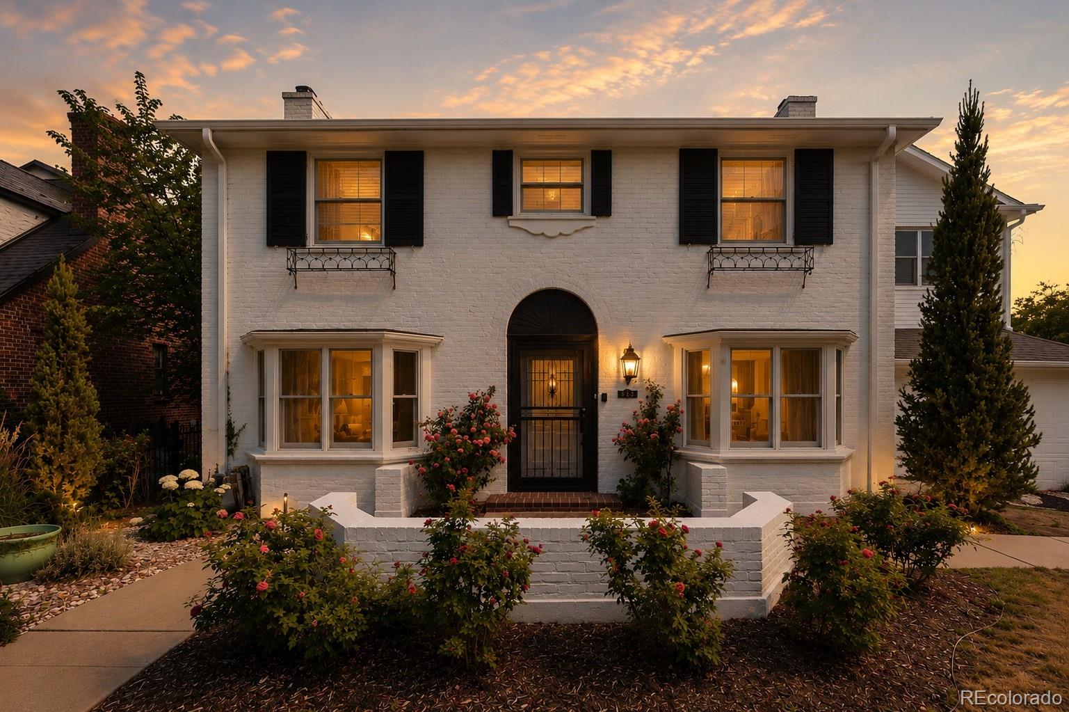 On a coveted corner of Denver's storied 6th Avenue Parkway, this 1937 Hilltop home tells a quiet story of timeless architecture brought thoughtfully into the present. Climbing roses frame the freshly painted brick and iron front door, and inside, the light-filled main level unfolds for both lively entertaining and easy everyday living. A formal living room with a classic mantel fireplace flows into your family room anchored by a striking navy herringbone tile wall, gas fireplace, and concrete hearth. The formal dining room opens to a true catering kitchen with wine storage while the chef's kitchen invites you to linger: quartz counters, professional stainless appliances, an oversized island, brass-and-glass pendants, and a sunny breakfast nook framing the backyard. A flexible bonus room with custom built-in desk works as office, study, or gym — with its own door to your private barrel sauna just steps beyond. A dramatic emerald-tiled powder bath adds the unexpected. Upstairs, the vaulted primary suite is a retreat all its own: sitting area, private balcony, dual walk-in closets, in-suite laundry, and a spa-caliber five-piece bath with freestanding tub and oversized marble shower. A second en-suite bedroom—now styled as an office—plus two more bedrooms and a full bath leave room to grow. Two lower levels add flexibility: a gym or media lounge, plus guest bedroom, full bath, and second laundry. Outside: rose gardens, raised beds, smart irrigation, xeriscaping, brick-paver patios, barrel sauna, and a two-car garage with charger. Impeccably maintained with dual HVAC, dual hot water, Ring security, and buried power lines that keep the street serene and storm-resilient — and solid brick that stays remarkably quiet, even on the Parkway. Zoned for award-winning Carson Elementary, with popular parks and trails close at hand. From the rose-lined entry to the sauna's warmth under the stars, every corner was designed for beautiful living. Welcome home.