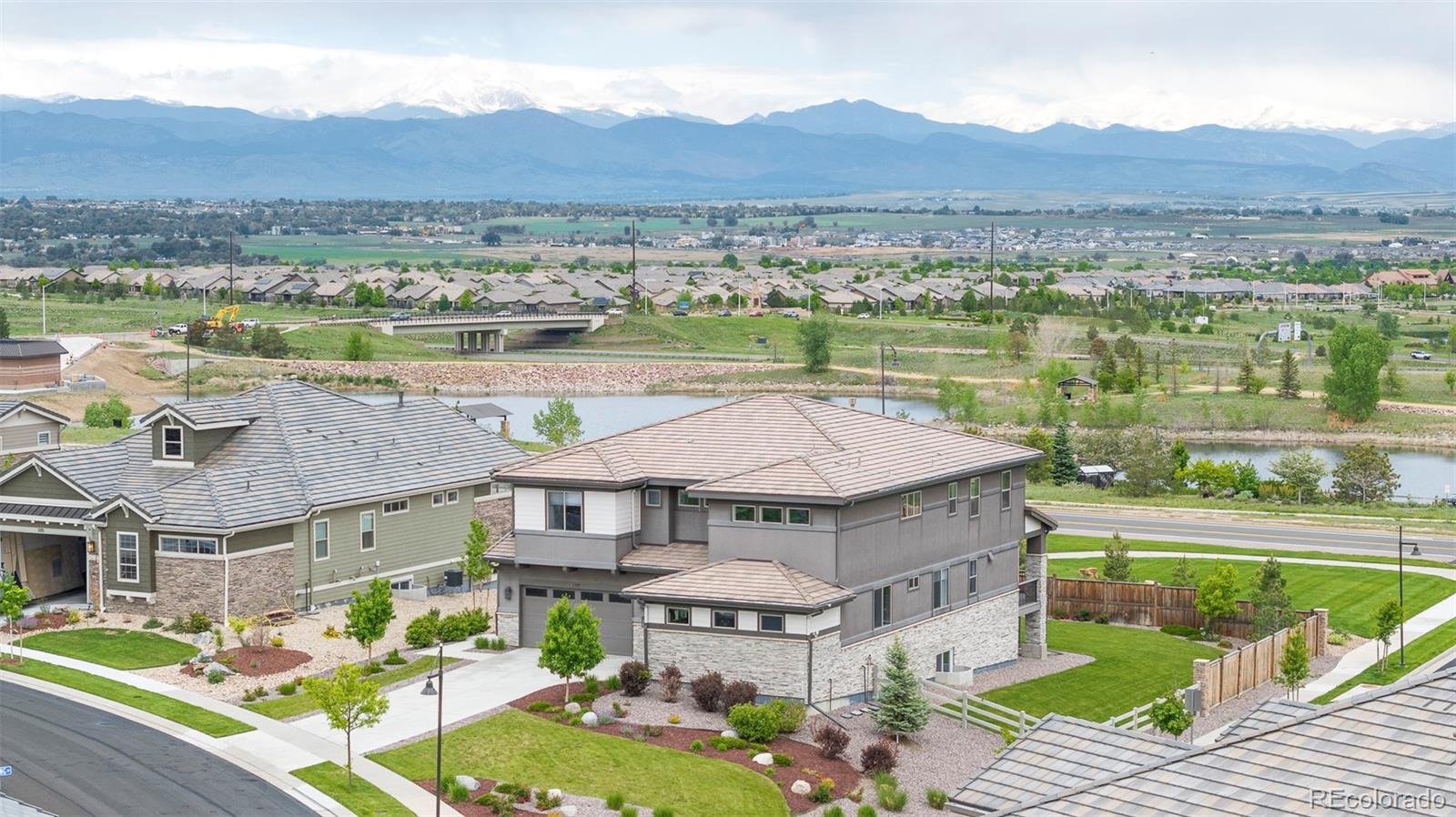 Where luxury meets nature-this former builder's model is ideally positioned on one of the largest premium corner lots, capturing sweeping views of Longs Peak, the Flatirons, and Sienna Reservoir. Every inch of this property showcases thoughtful craftsmanship, premium finishes, & intentional design that celebrates Colorado's natural splendor. Step into a soaring entryway that immediately impresses, leading into a sun-drenched great room with massive windows framing postcard-worthy vistas. The chef's kitchen is an entertainer's dream, anchored by a generous island & equipped with Sub-Zero & Wolf appliances, a beverage fridge, & a walk-in pantry. Wide-plank wood floors flow throughout the main level, where you'll also find a private office with built-ins & open views, & a main-level bedroom with an en-suite bath & walk-in closet. Retreat to the secluded primary suite upstairs-your personal sanctuary with a cozy gas fireplace, private terrace, & stunning mountain & water views. A spa-worthy five-piece bath features a soaking tub, oversized shower, & a walk-in closet. Three additional upstairs bedrooms & a spacious loft offer flexibility for family or guests. The lower level is designed for relaxation & entertainment, featuring a large rec room with a wet bar & fridge, a guest bedroom, & full bath. Modern conveniences include a wired security system, Tesla charger, solar-ready wiring, & epoxy-coated 3-car garage. Step outside to a peaceful covered deck & a backyard that opens to endless skies, walking trails, & the ever-changing natural beauty of Colorado. Watch hot air balloons in the fall, fireworks on holidays, & moonlight dance across the lake-all from the comfort of home. Residents enjoy access to the Anthem Rec Center, nearby charter schools, & effortless proximity to Boulder, Denver, & DIA. This is more than a home-it's a front-row seat to Colorado's most inspiring views.