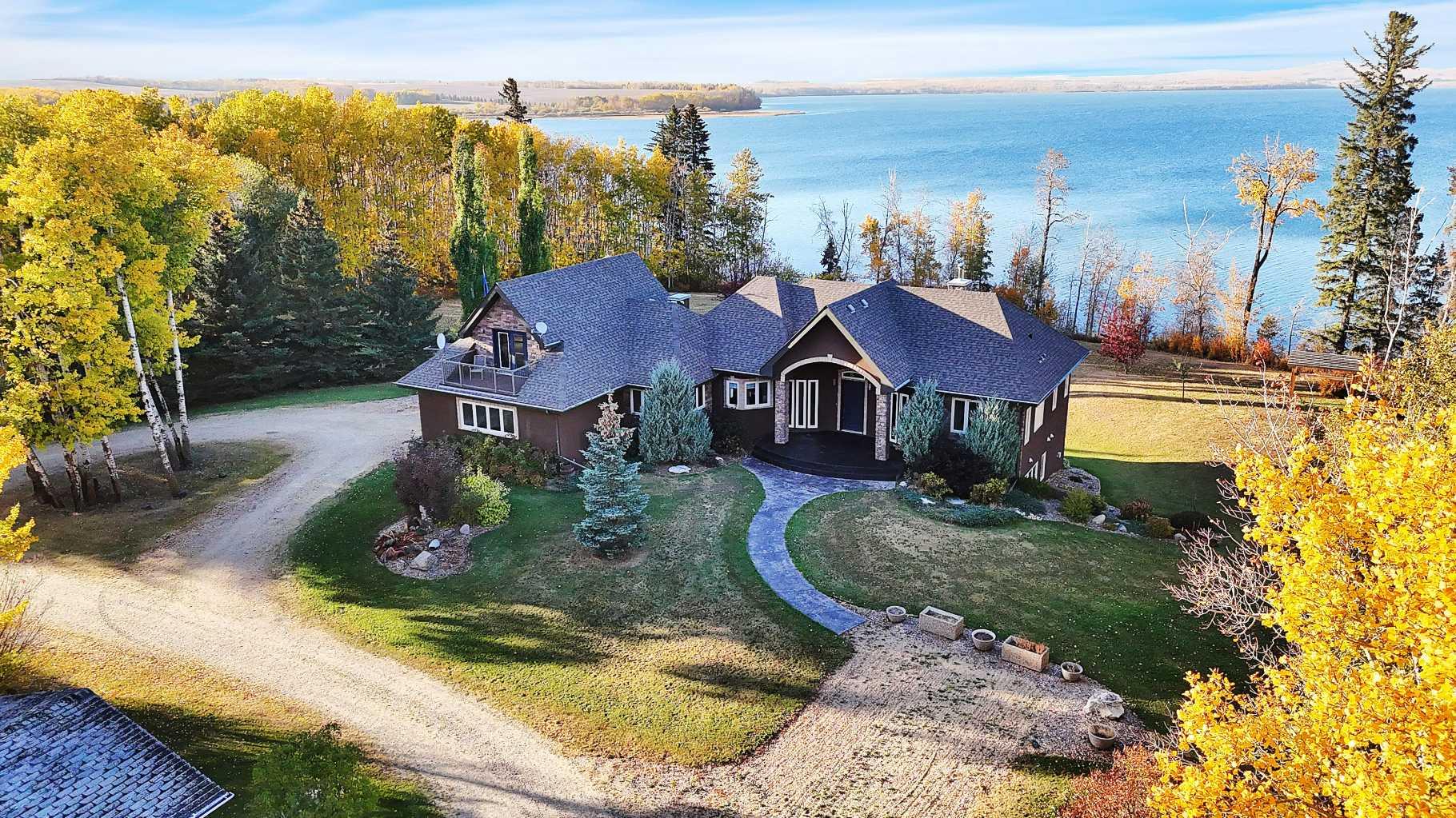 A rare opportunity to own an exceptional lakefront estate on 74 acres of prime Alberta countryside. This prestigious walkout bungalow offers an unmatched blend of luxury, privacy, and natural beauty, all with Riparian water rights. Located on 22108 Township Road 392 in Lacombe County, this residence exudes timeless elegance with custom finishes and breathtaking lake views throughout.Step inside to a chef-inspired kitchen, complete with granite countertops, custom cabinetry, and a layout designed for both daily living and entertaining. The expansive living room features coffered ceilings, a grand marble-faced fireplace, and floor-to-ceiling windows that showcase unobstructed water views.The primary retreat is a sanctuary of its own, with built-in cabinetry, panoramic lake-facing windows, a spa-inspired ensuite with walk-in shower, and an impressive walk-in dressing room. The lower level is built for entertaining, boasting a wet bar, spacious family room, and walk-out access to a covered patio, creating seamless indoor-outdoor living. Three large bedrooms downstairs offer comfort and scenic views.An additional finished space located above the garage provides extra flexibility for guests or workspace. Note: The secondary residence on the property is not part of the listing. Please do not access this area and respect all privacy signage during showings. Whether you're dreaming of a private retreat, family estate, or a legacy property, this home offers unparalleled lifestyle potential.