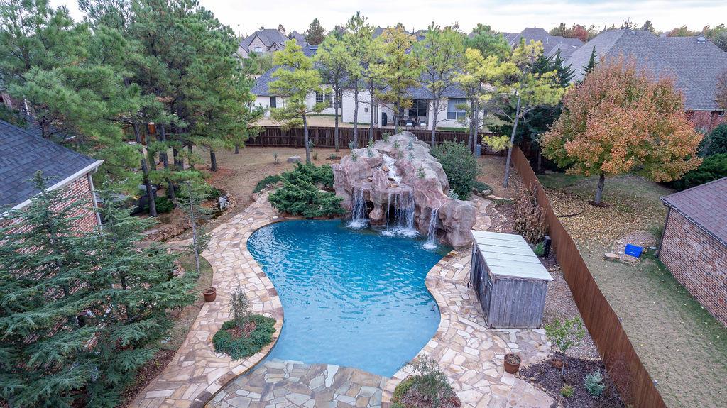 Set in the desirable northwest Edmond area, this custom property offers exceptional space, privacy, and convenience with quick access to top-rated schools, the turnpike, and both Edmond and Quail Springs amenities. Inside, the home features a well-planned layout with all bedrooms on the main level, a spacious bonus room with its own bath, and a standout kitchen designed for efficiency with multiple pull-out storage solutions, spice racks, hidden trash bin, pass-through window, and premium KitchenAid and JennAir appliances added between 2022–2025. Interior updates include new white oak flooring, fresh paint throughout, upgraded Delta double showerheads, enhanced bath finishes, and detailed wood trim touchups. The home also benefits from two newer AC units, Leaf Filters, new water heaters, a termite-prevention system, updated lighting, and a reinforced in-ground storm shelter. Outside, a Caviness-crafted resort-style retreat features a pool with beach entry, resurfaced grotto, swim-up bar with full kitchenette, waterfalls, a winding creek, expansive patio, fire pit, pool bath, and outdoor shower—an ideal environment for entertaining or unwinding. A rare RV-sized 4th garage provides exceptional storage alongside three additional bays, all supported by freshly updated fencing, gates, roof, gutters, shutters, and exterior trim. Don’t forget about the corner-lot setting in a gated neighborhood with pond trails and quiet streets. And don’t miss out on the extensive attic storage, built-in speaker system, dimmable lighting, and thoughtful organizational features that elevate everyday living. A home with this level of craftsmanship and resort-style amenities is truly uncommon in the Edmond market—come see what makes it stand out.