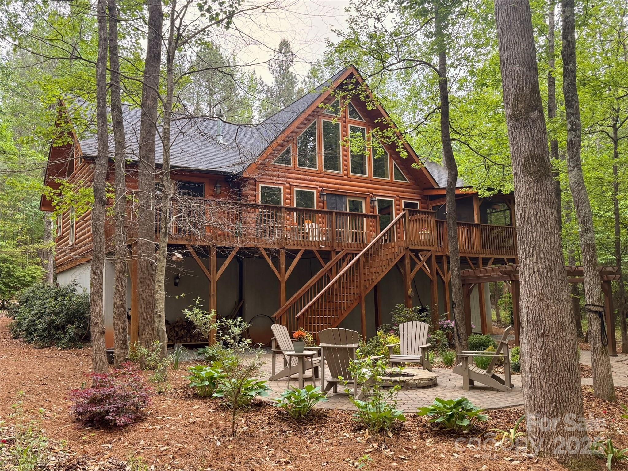 Your Private Log Home Retreat Awaits! Tucked away at the end of a private drive, this stunning custom-built 1.5-story log home with a full basement offers the perfect blend of rustic charm and modern convenience. With 3 bedrooms and 3 baths, every detail has been thoughtfully designed to create a warm and inviting retreat. The soaring 23+ foot ceilings with exposed beams, gleaming hardwood floors, wall-to-wall windows, and a cozy Jotul gas stove make the great room the heart of the home. The chef’s kitchen features a 6-burner gas range, hickory cabinets, granite countertops, breakfast bar, and spacious dining area that flows seamlessly onto the screened porch—perfect for entertaining with wooded views as your backdrop. The main-level owner’s suite offers a peaceful escape with a jetted tub, separate shower, double vanity, and walk-in closet with custom shelving.