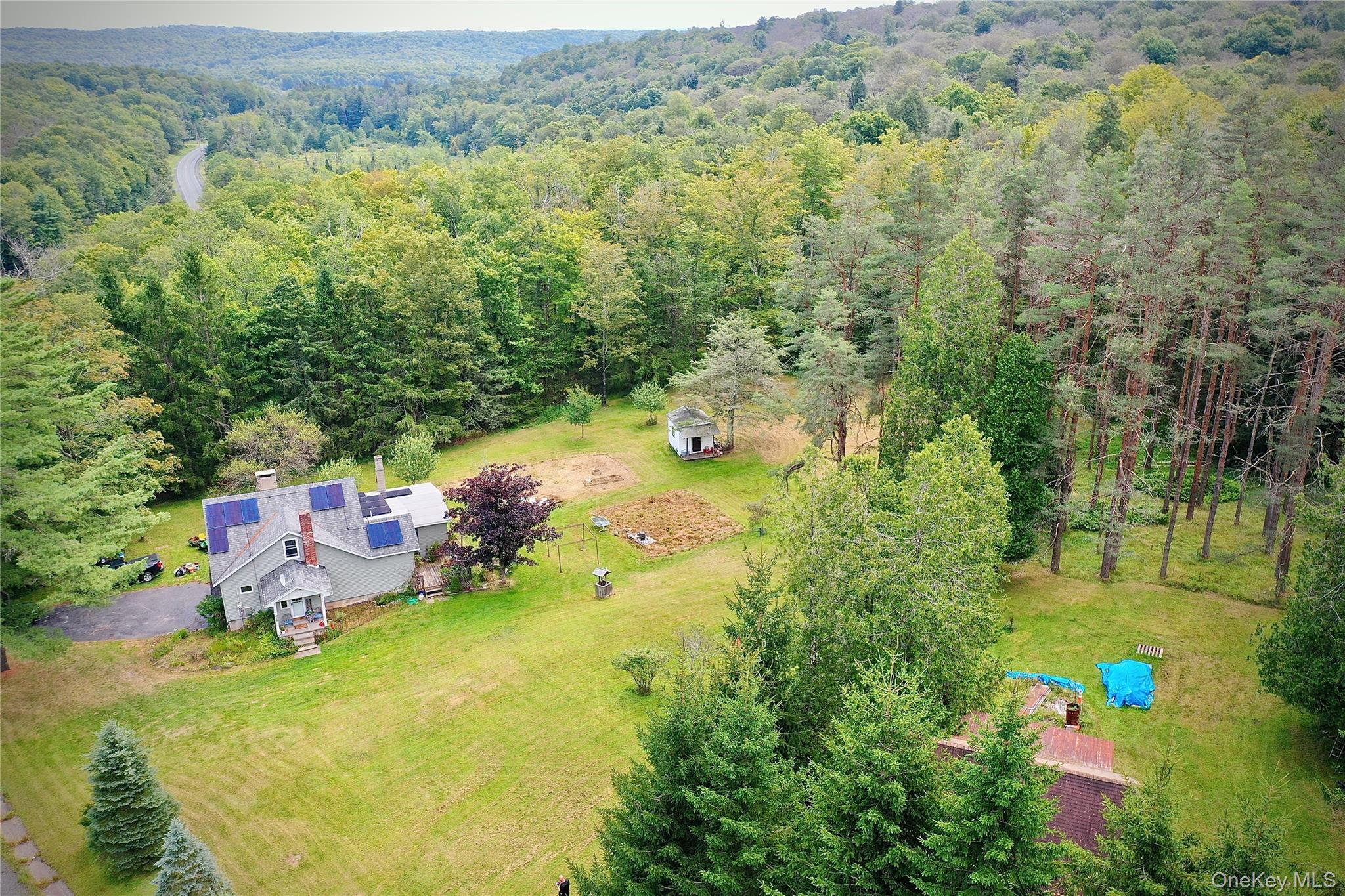 Aerial view of property and surrounding area with a heavily wooded area