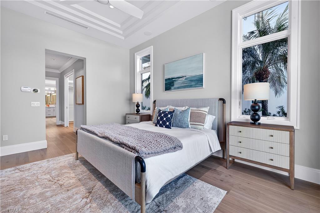 Bedroom featuring light wood-type flooring, ornamental molding, and a raised ceiling