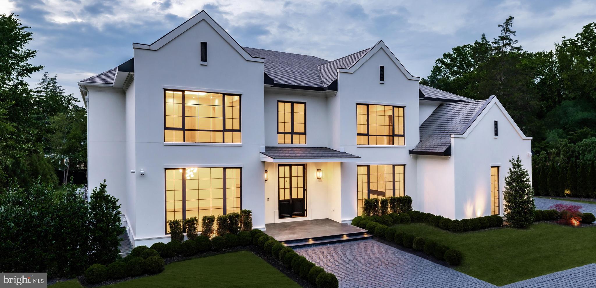 A new crown jewel in McLean, developed by Ambar, 1102 Chain Bridge Road commands attention in the prestigious Langley Farms enclave. A newly constructed triumph that fuses contemporary elegance with transitional château attributes, this estate is tailored for the digital age yet crafted with an artisanal touch seldom seen today. Spanning over 16,000 square feet, it is a showcase of forward-thinking design and enduring craftsmanship.Set on a rare 0.8-acre lot, the approach reveals a gracious cobblestone motor court enveloped by sleek, mature privacy landscaping. Beyond grand double doors, a herringbone-floored foyer offers clear sightlines through the home’s depth, introducing 12-foot ceilings, solid walnut floating stairs, and 10-foot custom wood doors with Emtek hardware. These are testaments to the home's exacting attention to detail. Wide-plank engineered floors and recessed crown uplighting provide a refined warmth throughout.Designed equally for grand entertaining and everyday comfort, the main level flows effortlessly between formal and informal spaces. At its center is an aspirational chef’s kitchen: dual waterfall islands clad in Spanish marble, Italian composite cabinetry, a vintage Viking 8-burner range, and a full Miele suite. A separate, fully enclosed spice kitchen with its own Miele appliances adds further versatility.Three floor-to-ceiling collapsible glass walls open to reveal true indoor/outdoor resort living. A covered patio offers ideal al fresco dining, while the marble terrace introduces a stunning heated lap pool with spa, waterfall, hidden drainage, and an automatic cover. A private guest suite with direct patio access and panoramic pool views is quietly tucked away on the main level.Upstairs, the primary suite is a sanctuary of serenity. Beyond a long corridor and double doors lies a generous sleeping room and private sitting area, divided by a custom linear fireplace. Two sets of French doors open to a private terrace with sweeping views. The spa-inspired bath is clad in Dekton and features radiant heated floors, eight shower heads, a Kallista soaking tub, dual water closets, and separate his-and-hers dressing rooms outfitted in custom Italian cabinetry with illuminated glass displays and center islands.Additional upper-level bedrooms are grand in scale, each with tray ceilings, custom walk-in closets, and designer en suite baths. A convertible nursery offers discreet access to the primary suite. A spacious laundry room with dual islands and full-height cabinetry completes the upper level.The lower level is designed for elevated recreation and wellness. Amenities include a professional home cinema, a full bar with a Dekton island, and a fireside lounge wrapped in Porcelanosa tile. A secure safe room with 36-inch concrete walls and a Fort Knox vault door offers peace of mind. The wellness wing is a true retreat, with a steam shower, commercial sauna, fitness studio, and walk-up access to the outdoors.Engineered for longevity and performance, the home features a commercial-grade elevator, 600-amp electrical service, copper plumbing, five Carrier HVAC zones, and dual 80-gallon water heaters. Infrastructure is in place for a full-house gas generator. A central security suite monitors the 8-camera system, while a sophisticated URC system provides integrated control of Lutron lighting and concealed surround sound via in-wall iPads and smartphones.The 54-foot four-car garage with soaring ceilings is a dream for the automobile enthusiast. Meticulous landscaping and artful hardscaping unify the estate’s bold presence with its refined aesthetic. With commanding architecture and an unrivaled array of modern amenities, 1102 Chain Bridge Road stands as one of the Capital Region’s most exceptional residential offerings.